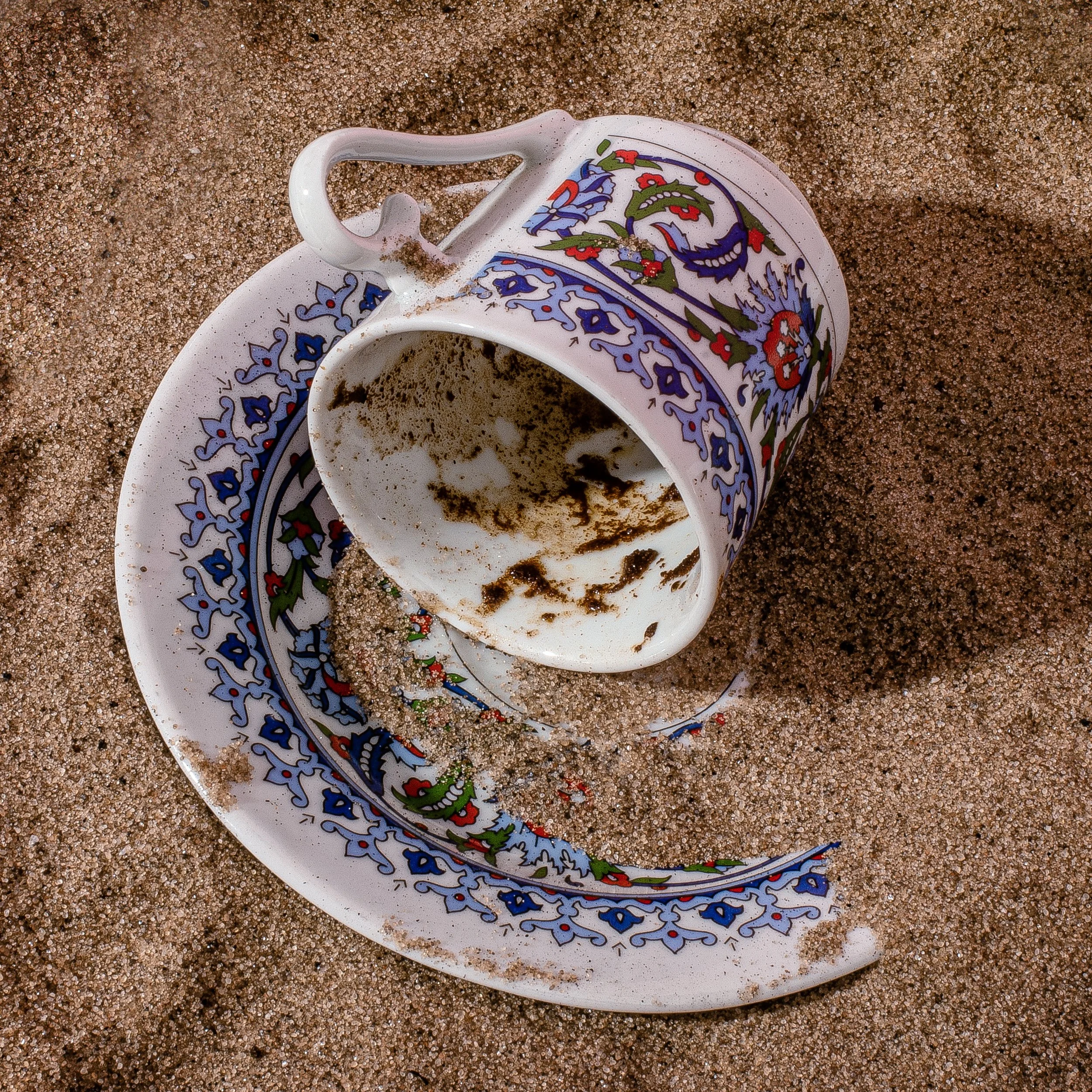 Overturned hand-painted Turkish coffee cup with grounds on sand, used for tasseography fortune reading at Dr. Honeybrew's NYC coffee room