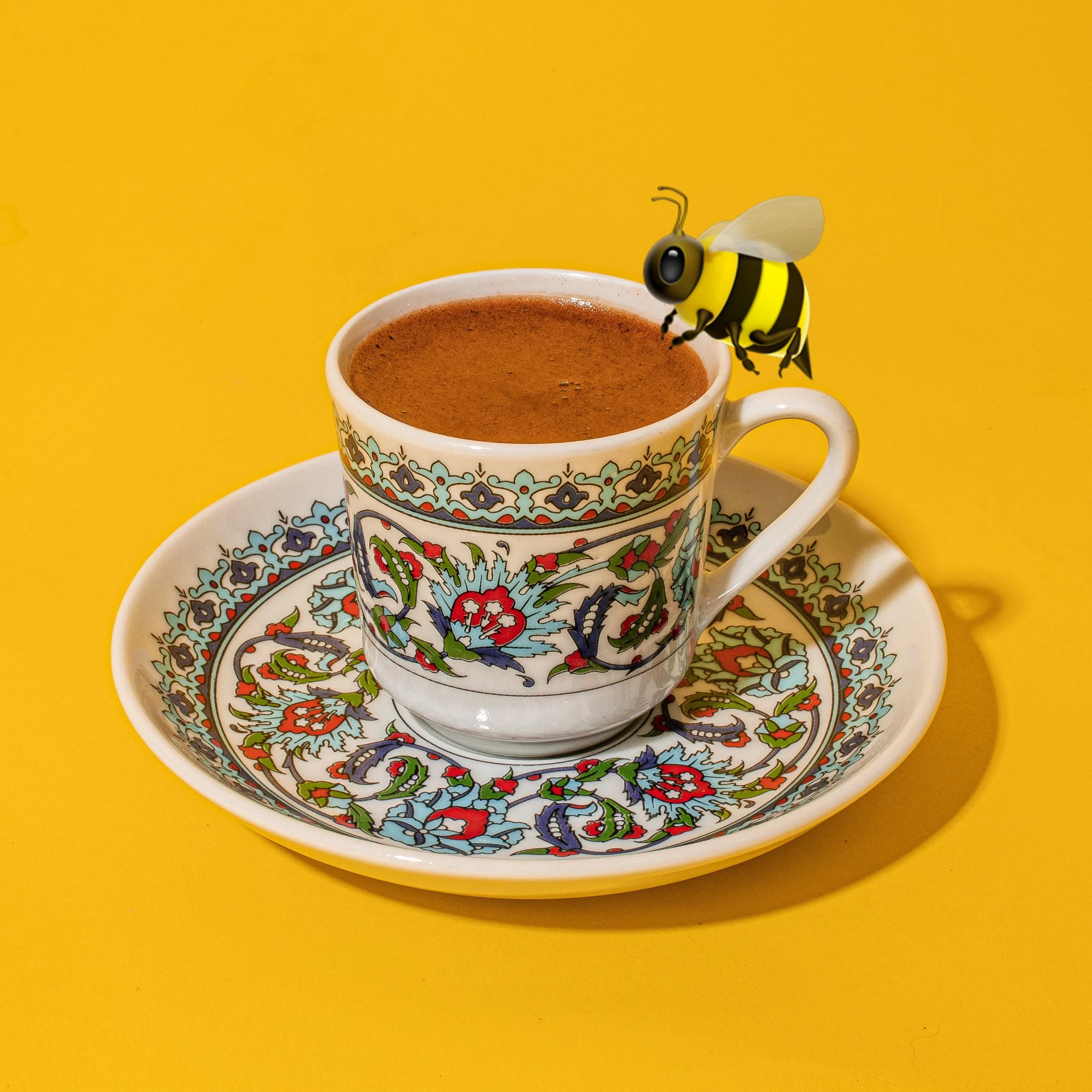 Traditional Turkish coffee served in a hand-painted ceramic cup and saucer with a bee emoji at Dr. Honeybrew's Turkish Coffee Room in New York City