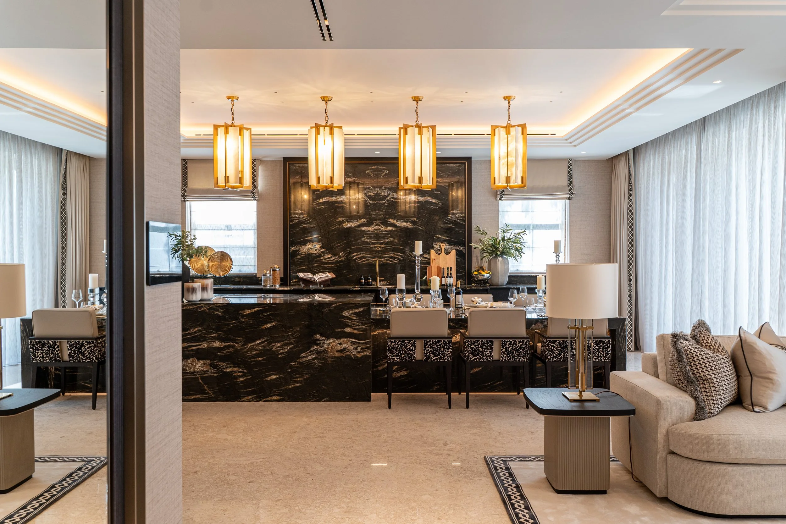 Luxurious hotel or restaurant interior with modern decor, pendant lighting, marble feature wall, dining tables, and a seating area with pillows and lamps.