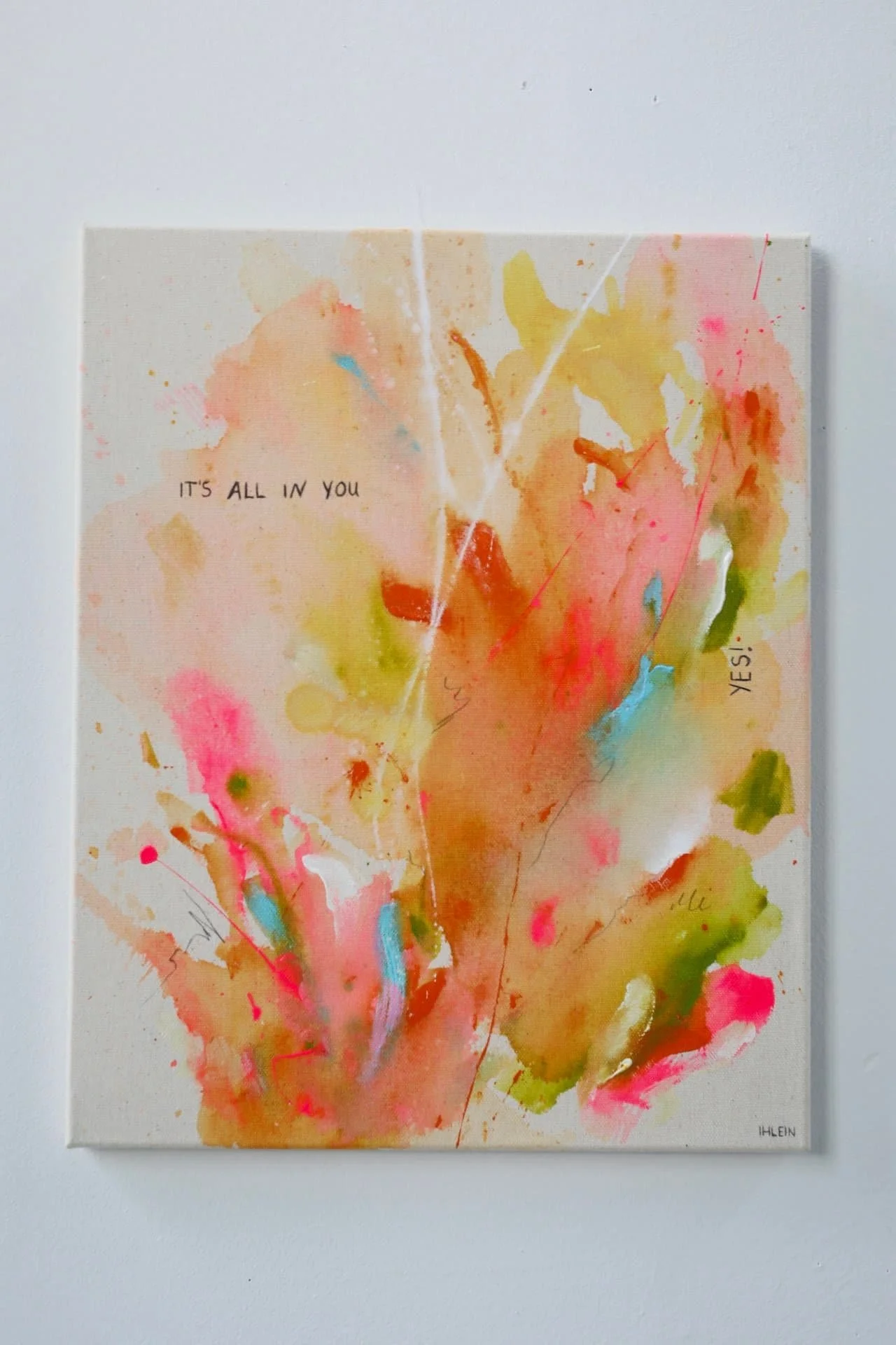 Ein abstraktes Kunstwerk mit bunten Farbklecksen und Pinselstrichen, das den Spruch 'IT'S ALL IN YOU' enthält.