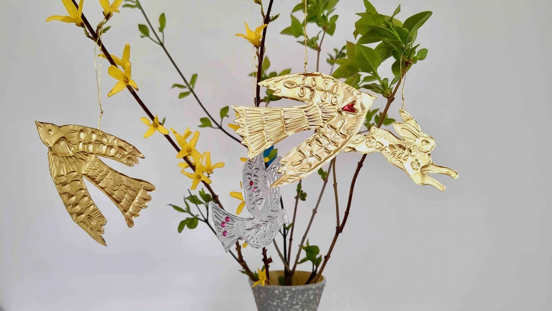 Mehrere Ästen mit grünen Blätter und Anhänger aus goldenen und silbernen Folie