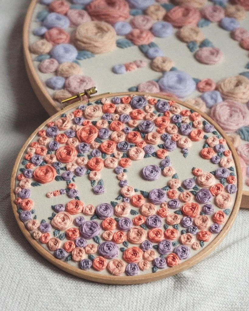 Stickrahmen mit vielen kleinen Rosen in lila, rosa, orange. Spruch 'Fuck'