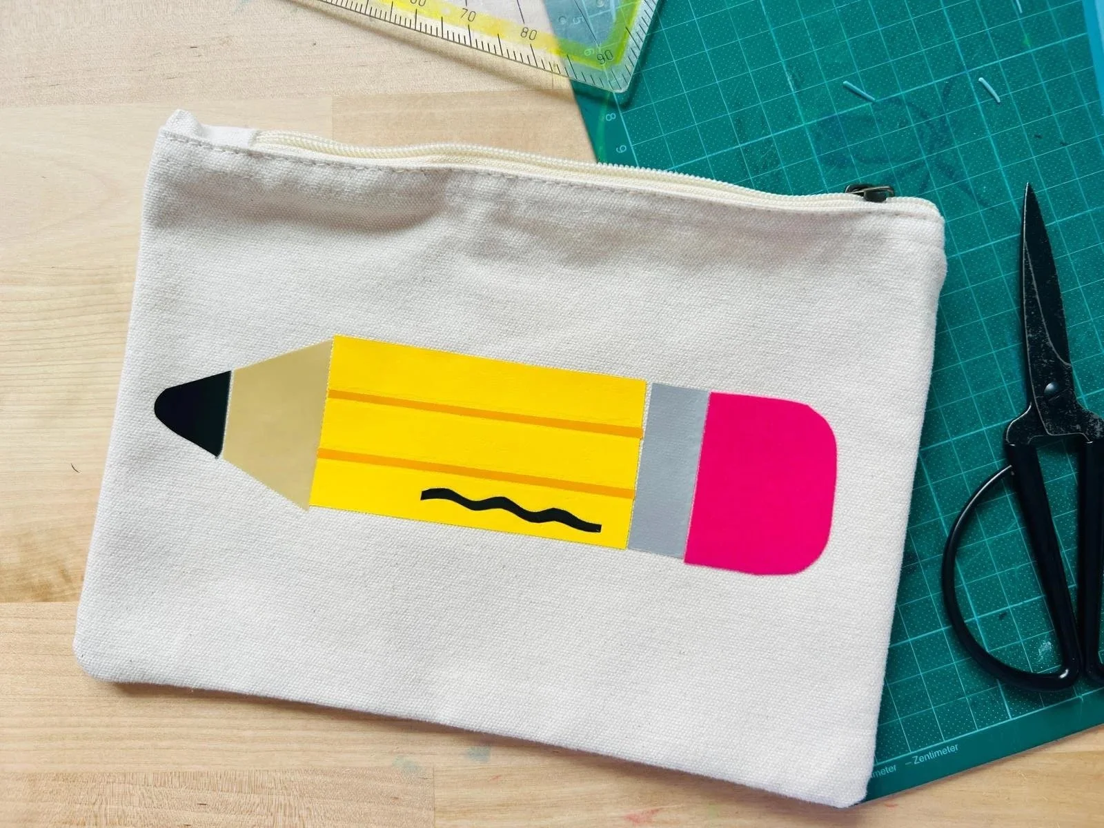 Kosmetiktasche in beige mit dem Motiv eines großen Bleistiftes
