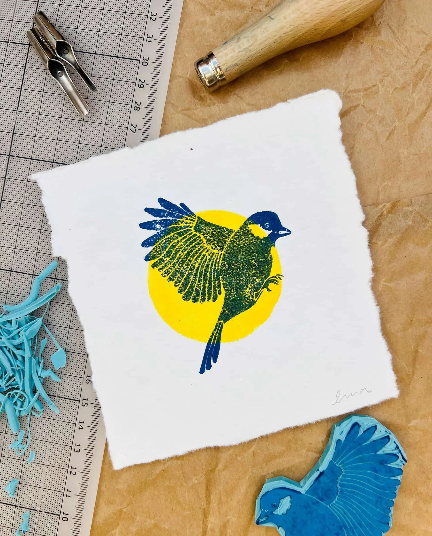 Abdruck vom einem Vogel in blau und gelber Sonne drum herum