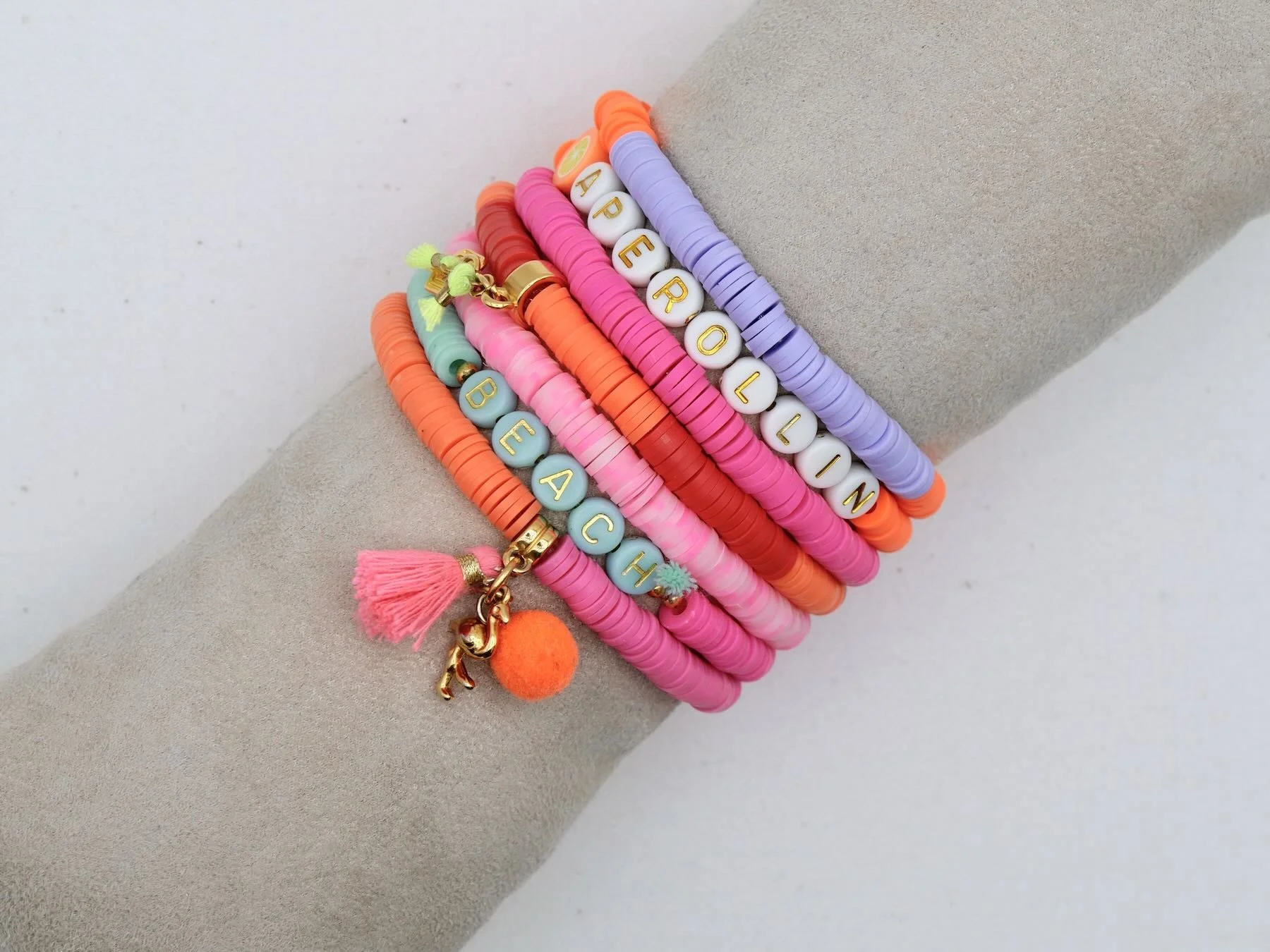 Sieben bunte Armbänder in rosa, rot, lila, weiß, türkis, mit Quasten, Pompons und Buchstaben