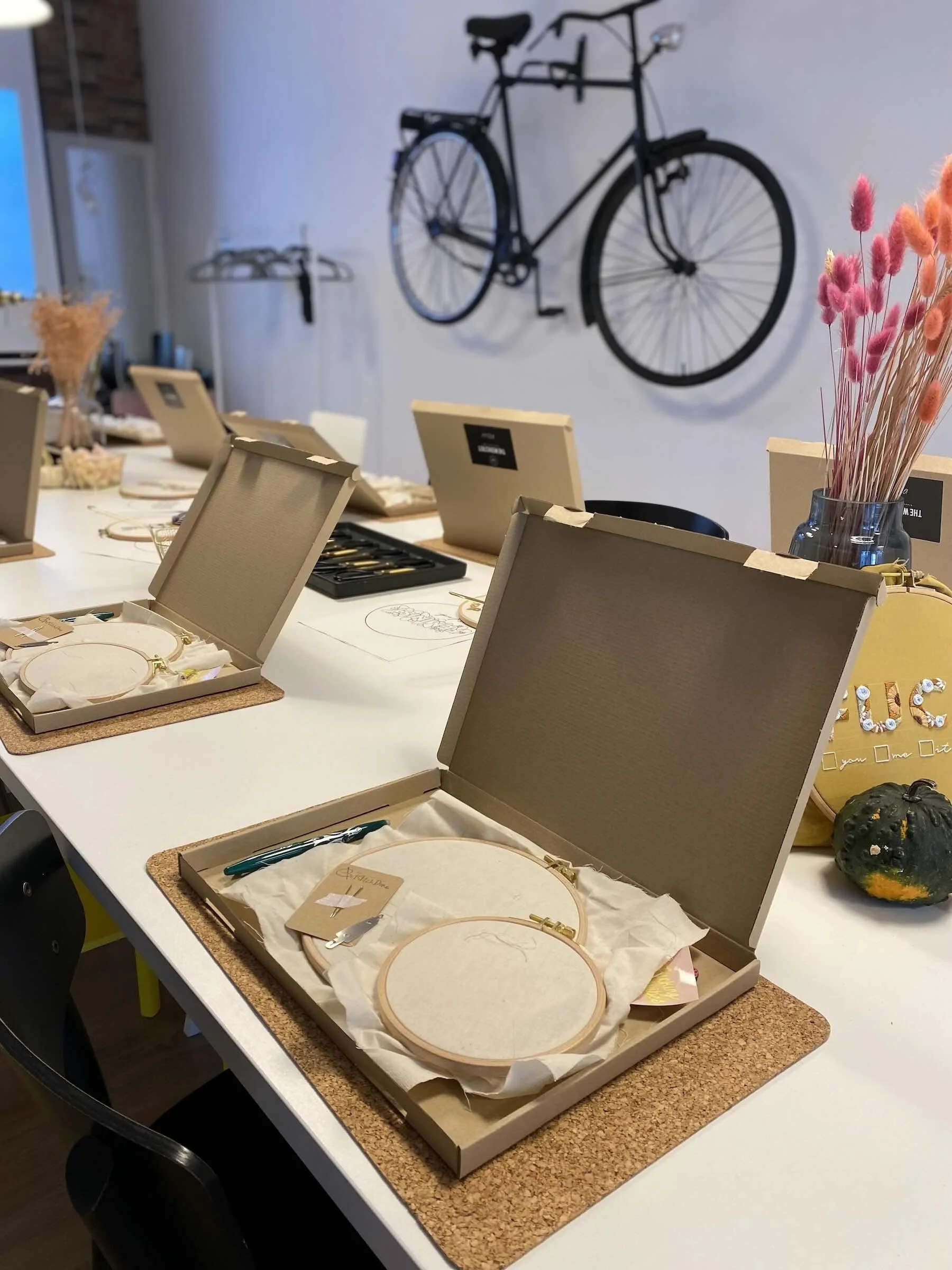 Kartons mit Stickzubehör und Stickrahmen liegen auf dem Tisch. Fahrrad im Hintergrund