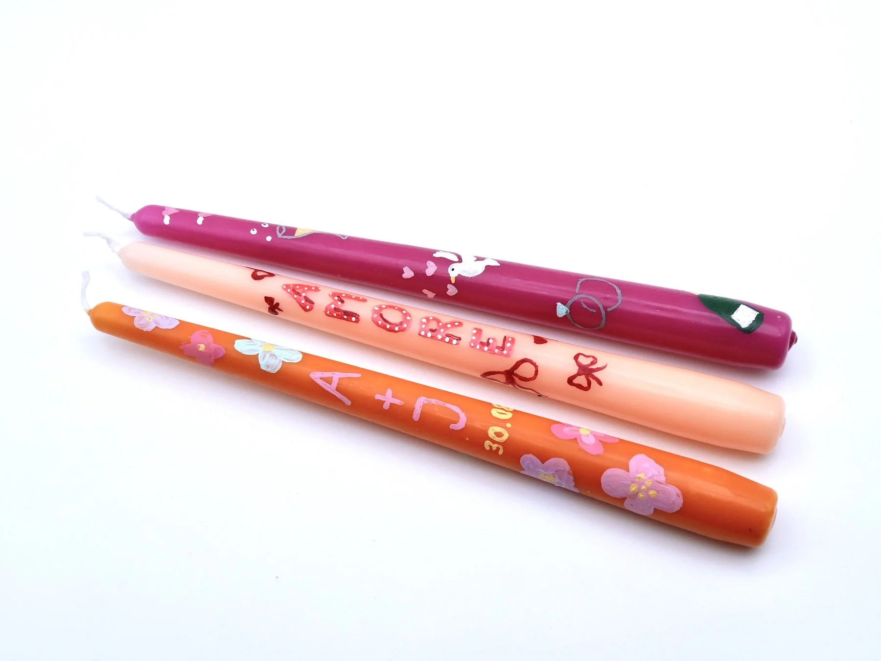 Stabkerzen in orange, rosa, pink bemalt mit kleinen Blumen und Buchstaben Motiven