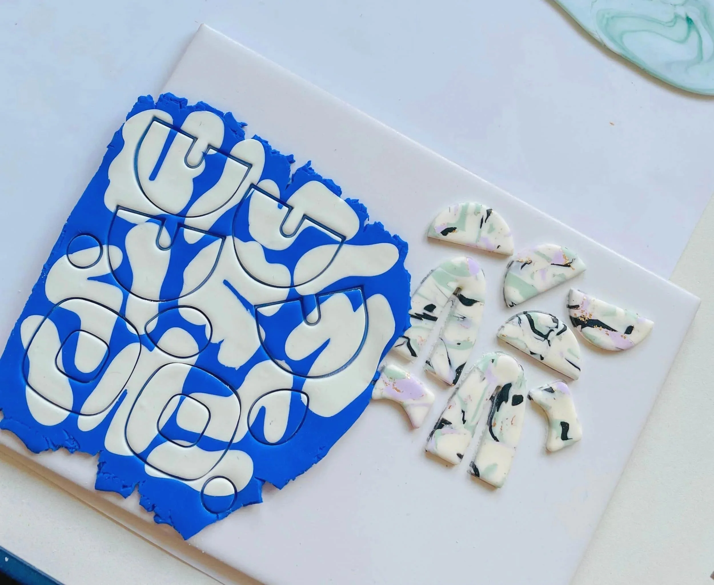 Blau weiße Polymer Clay Masse ausgerollt und ausgestochen in verschiedene organische Formen