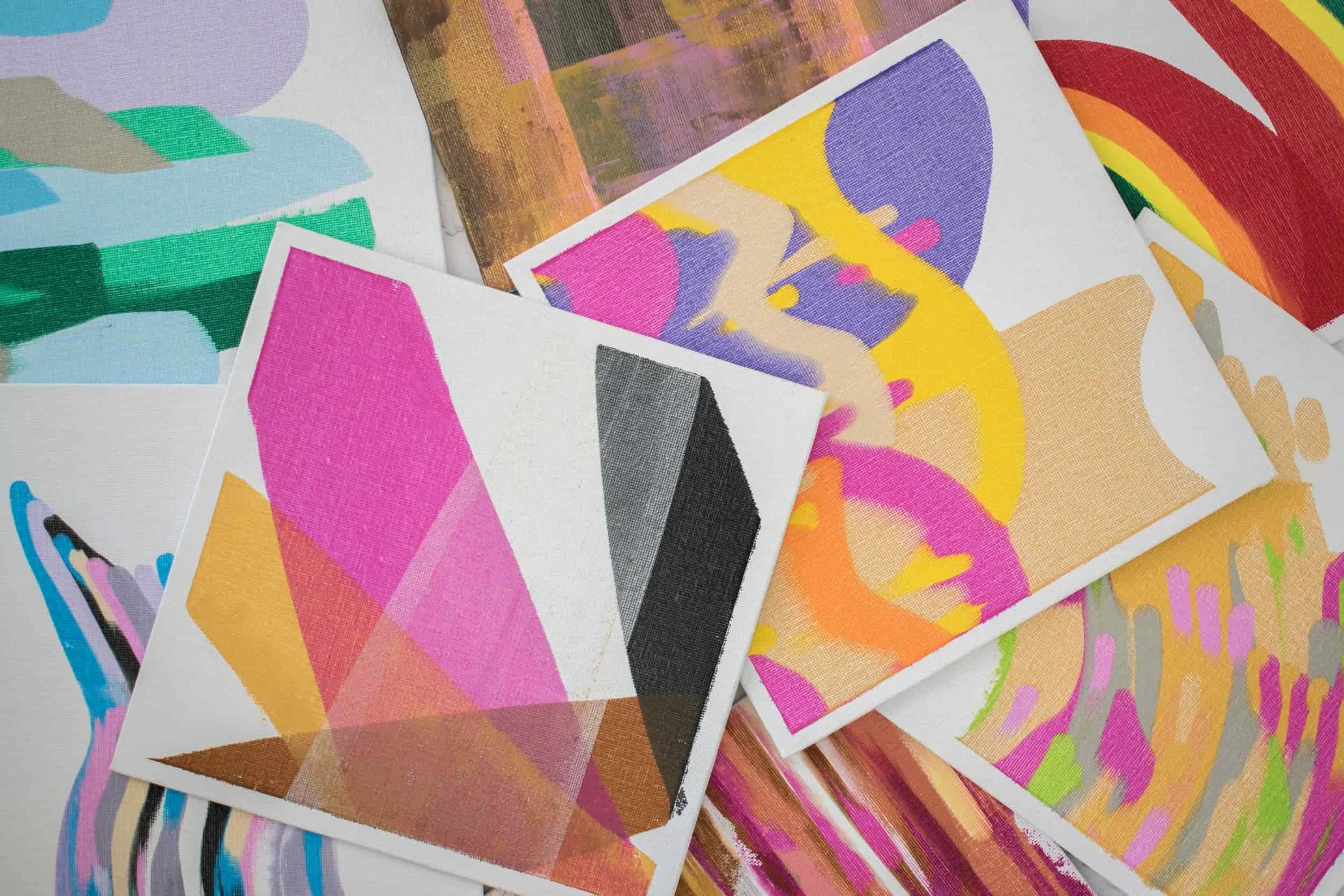 Mehrere bunte, abstrakte Gemälde mit geometrischen und organischen Mustern, auf Papier oder Leinwand, in einer künstlerischen Anordnung.