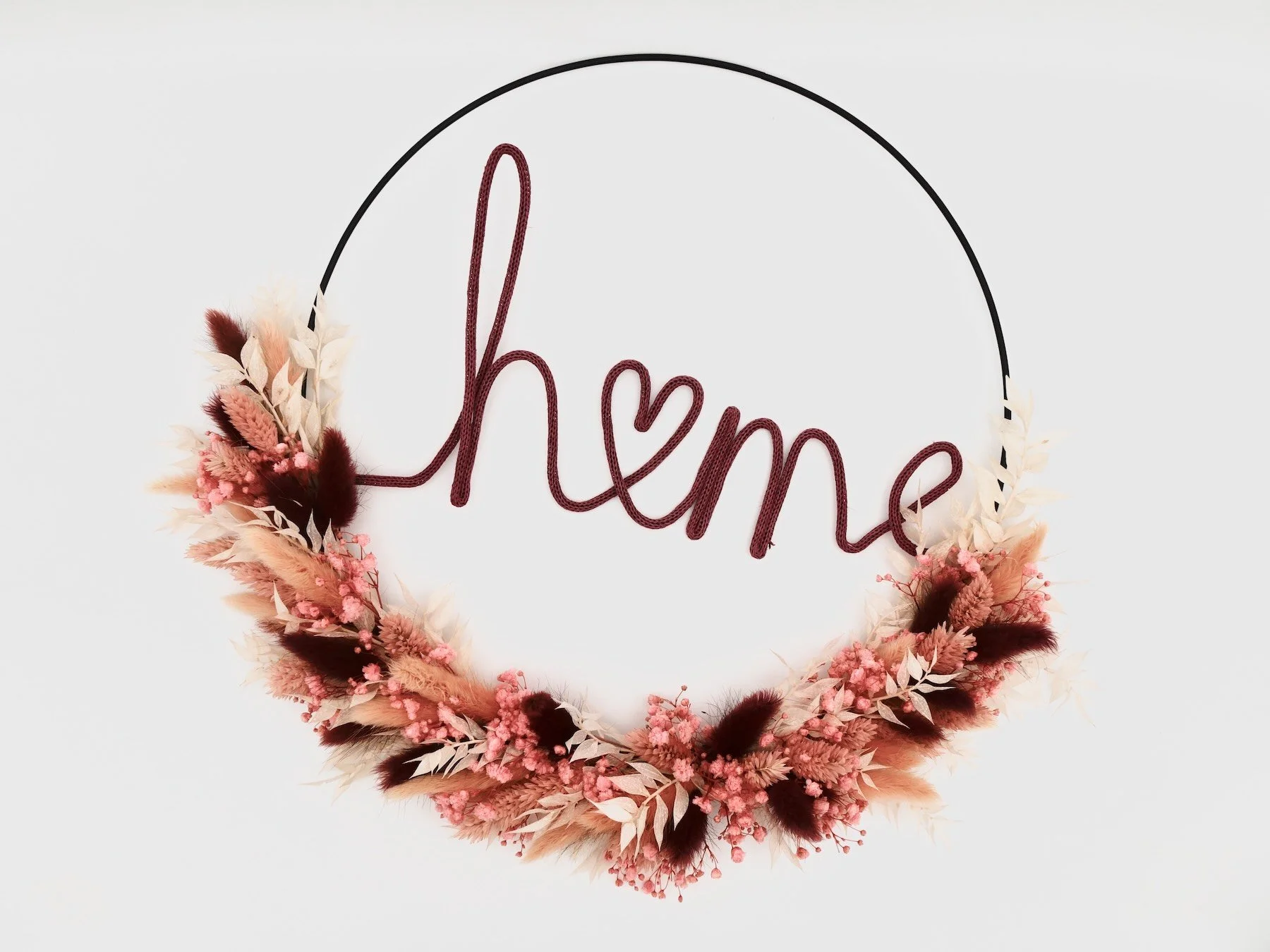 Schwarzer Metallring umwickelt mit bunten Trockenblumen in verschiedenen Farben, darunter dunkelrot, rosa, gelb und weiß. Schriftzug 'Home'