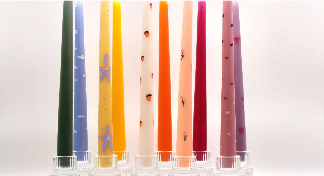 Mehrere bunte bemalte Kerzen in blau, gelb, weiß, pink, rosa, orange