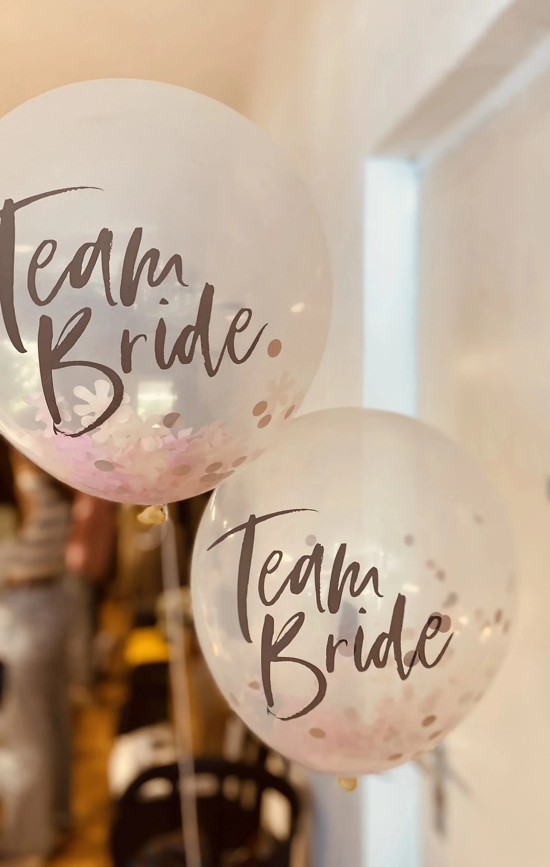 Zwei Luftballons mit Beschriftung 'Team Bride' und bunten Konfetti drin
