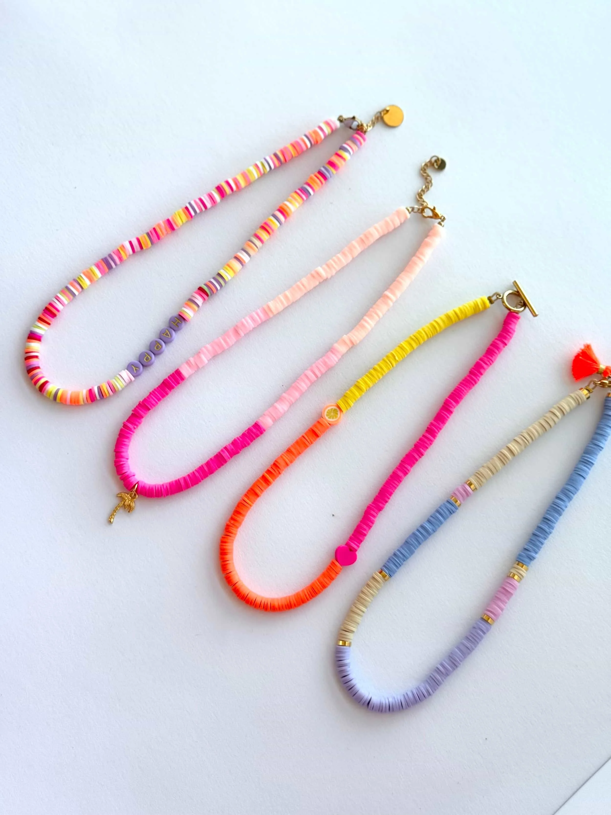 Fünf bunte Halsketten aus kleinen Katsuki Perlen in verschiedenen Farben auf weißem Hintergrund.