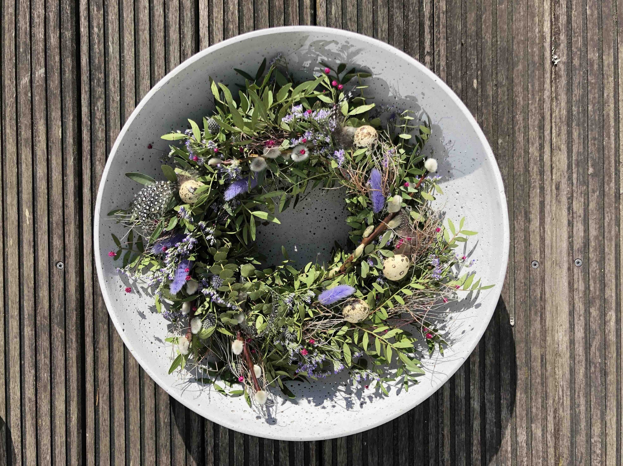 Kranz aus frischen grünen Zweigen, bunten Blumen, Federn und Eiern