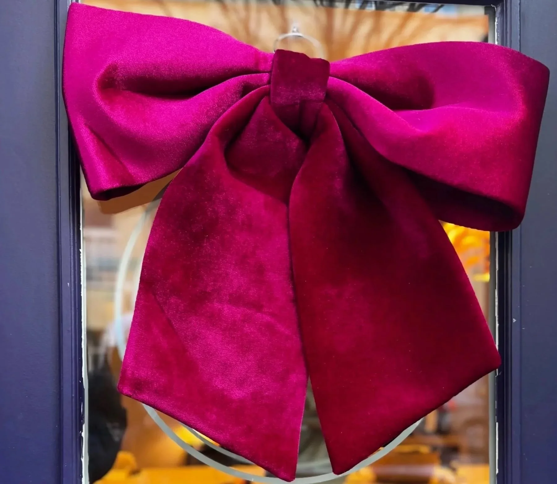 Riesige Schleife in magentapink hängend an einer Glastür