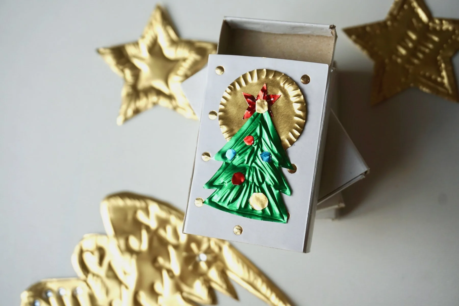 Tannenbaum mit Baumschmuck und goldenem Stern aus Prägefolie auf einem kleinem Karton