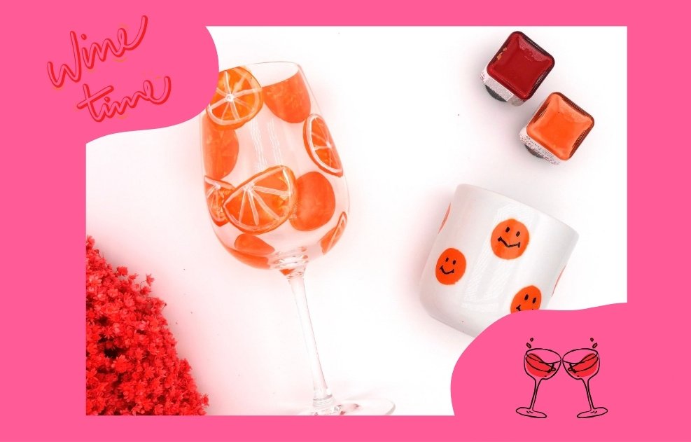Weinglas bemalt mit Orangenscheiben und kleiner weißer Becher ohne Henkel bemal mit Smileys in orange 