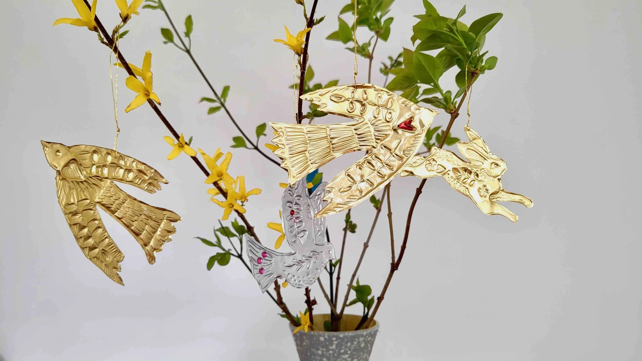 Mehrere Ästen mit grünen Blätter und Anhänger aus goldenen und silbernen Folie