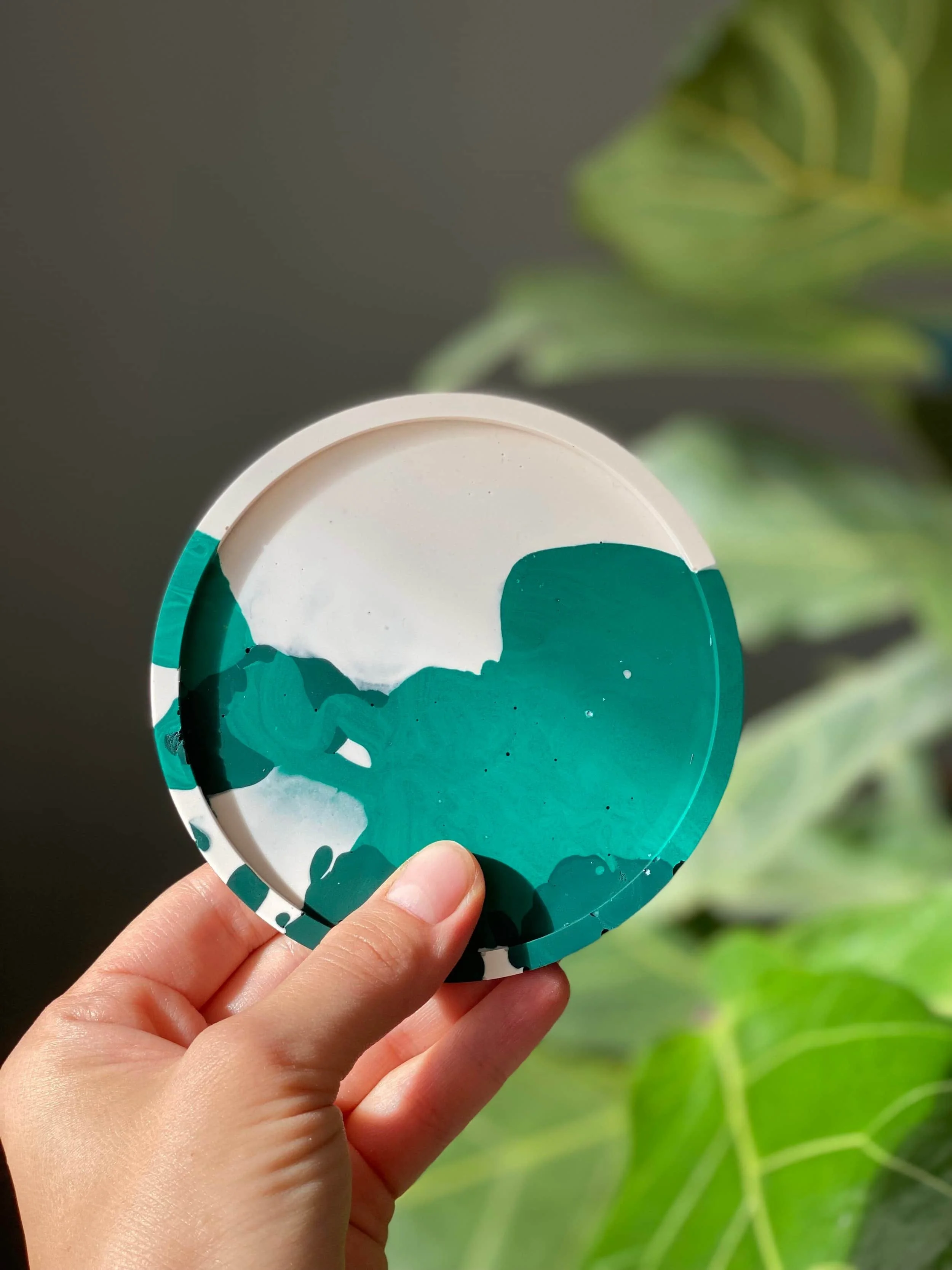 Hand hält runde Schale mit weiß-grünen Farbverläufen aus Jesmonite