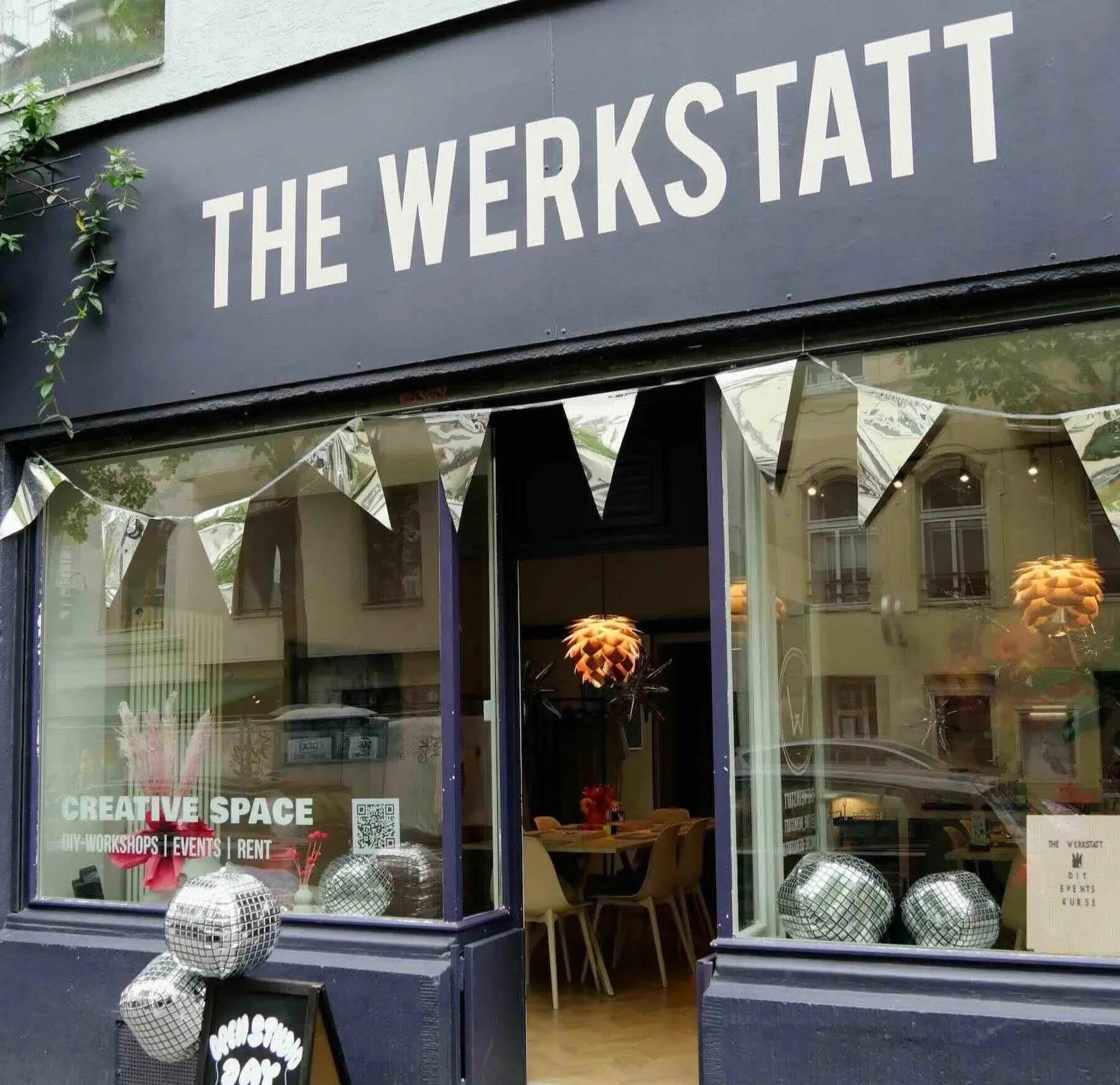 Ladenlokal Fensterfront in dunkellila mit der Schrift 'The Werkstatt' und einer silbernen Wimpelkette