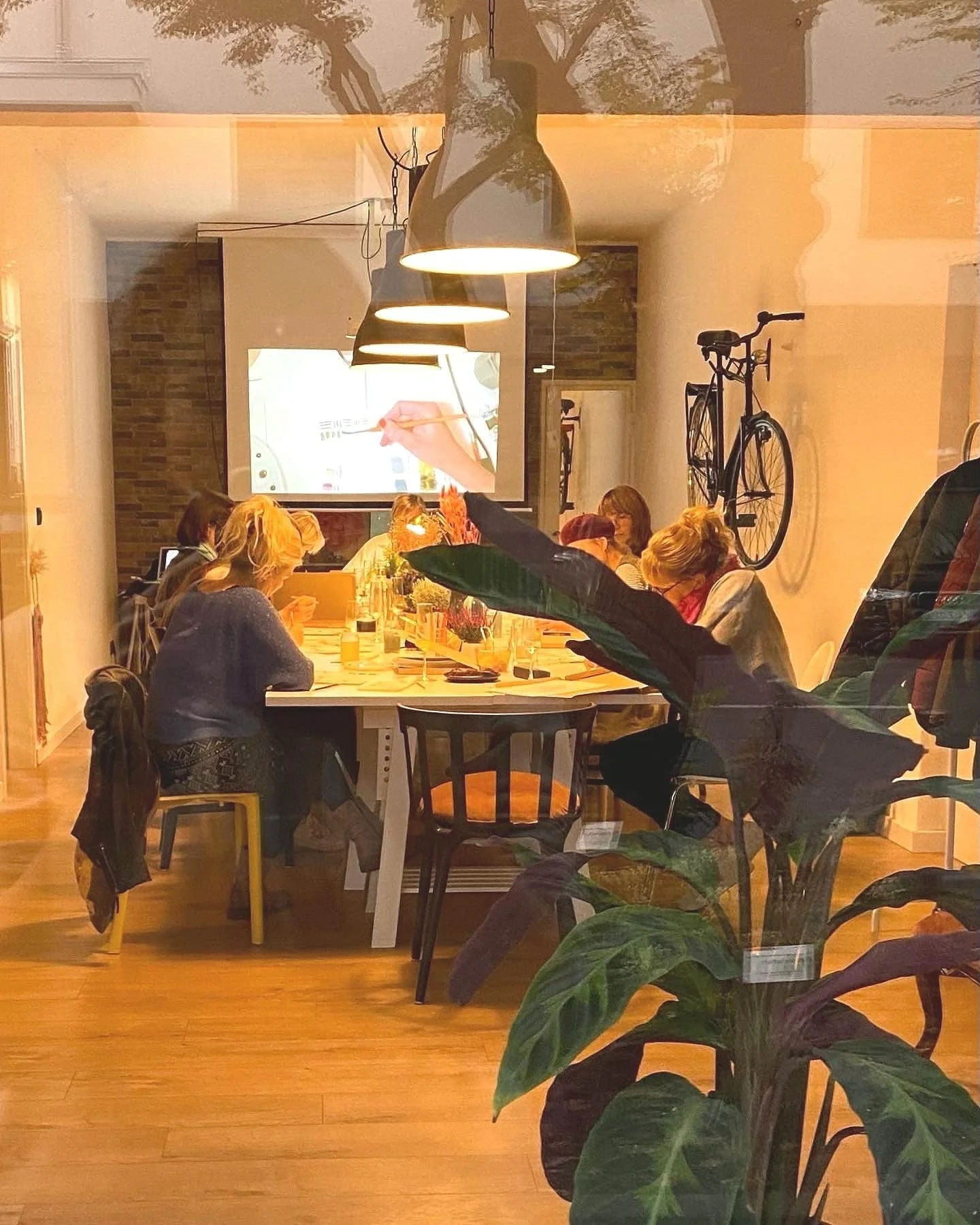 Kreativere Workshop Raum mit Personen an einem Tisch, im Hintergrund eine Anleitung auf einer Leinwand