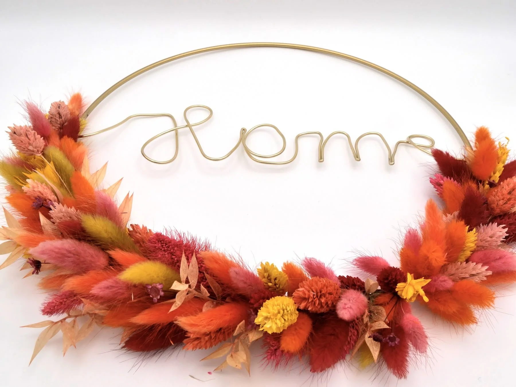 Goldener Metallring umwickelt mit bunten Trockenblumen in verschiedenen Farben, darunter rot, orange, gelb und dunkelrot. Schriftzug 'Home'