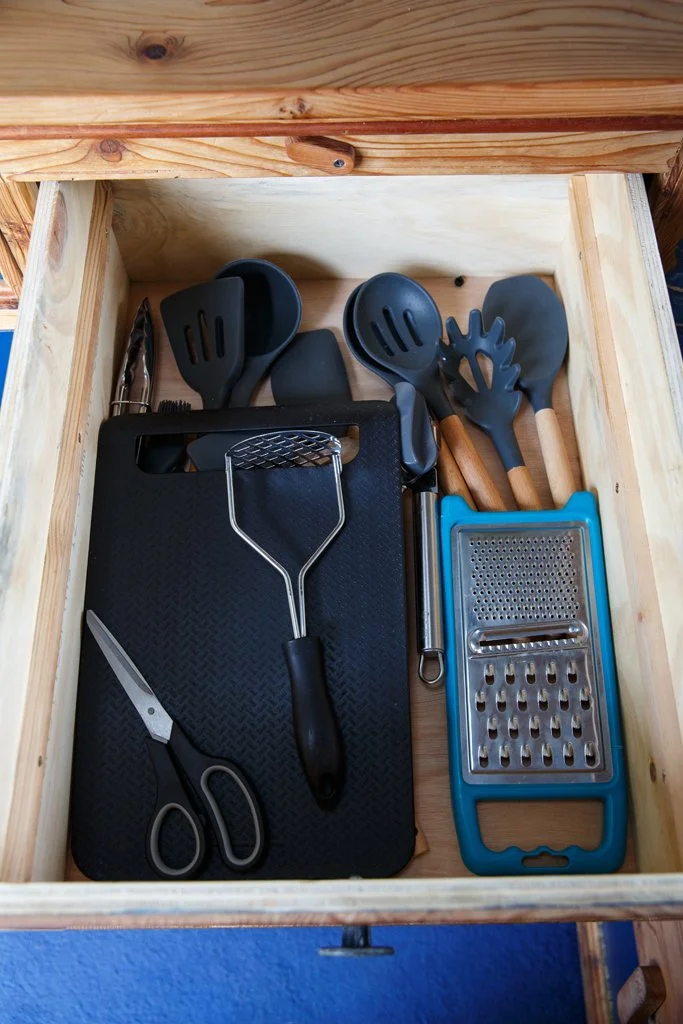 Fully equipped campervan kitchen drawer with utensils, chopping boards and cookware, thoughtfully organised for easy self-catering on the road. Azure includes everything you need for relaxed motorhome holidays from Bristol, whether cooking at campsit
