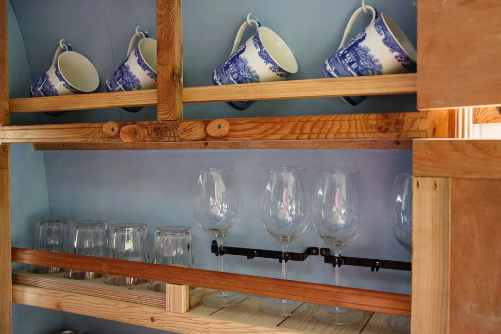 Thoughtful interior storage in Azure, with tea cups and wine glasses neatly stored for relaxed campervan motorhome hire from Bristol.