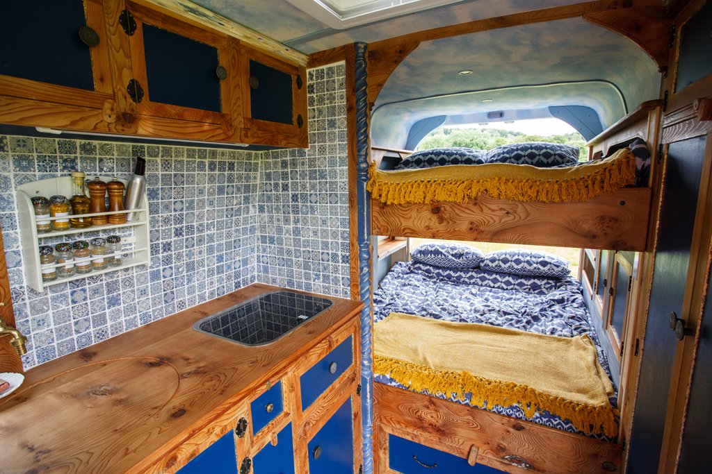 Azure’s beautifully crafted interior showing the comfortable sleeping area alongside the handcrafted kitchen, ideal for relaxed campervan motorhome hire from Bristol.