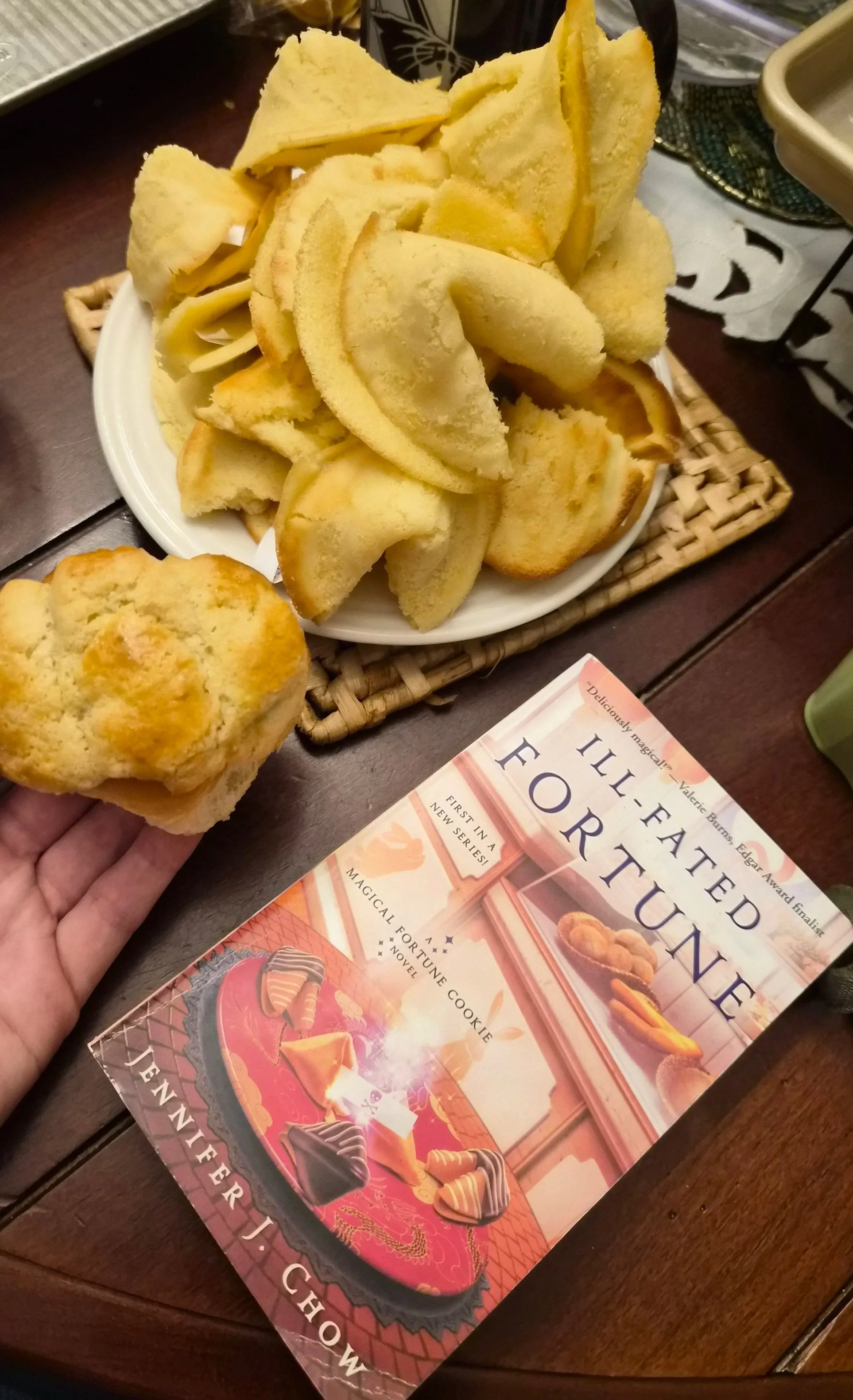 Homemade fortune cookies and pineapple buns next to the book Ill-Fated Fortune