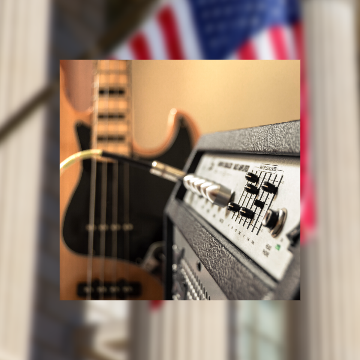 Close-up of a guitar amplifier with knobs and sliders, and an acoustic guitar in the background.