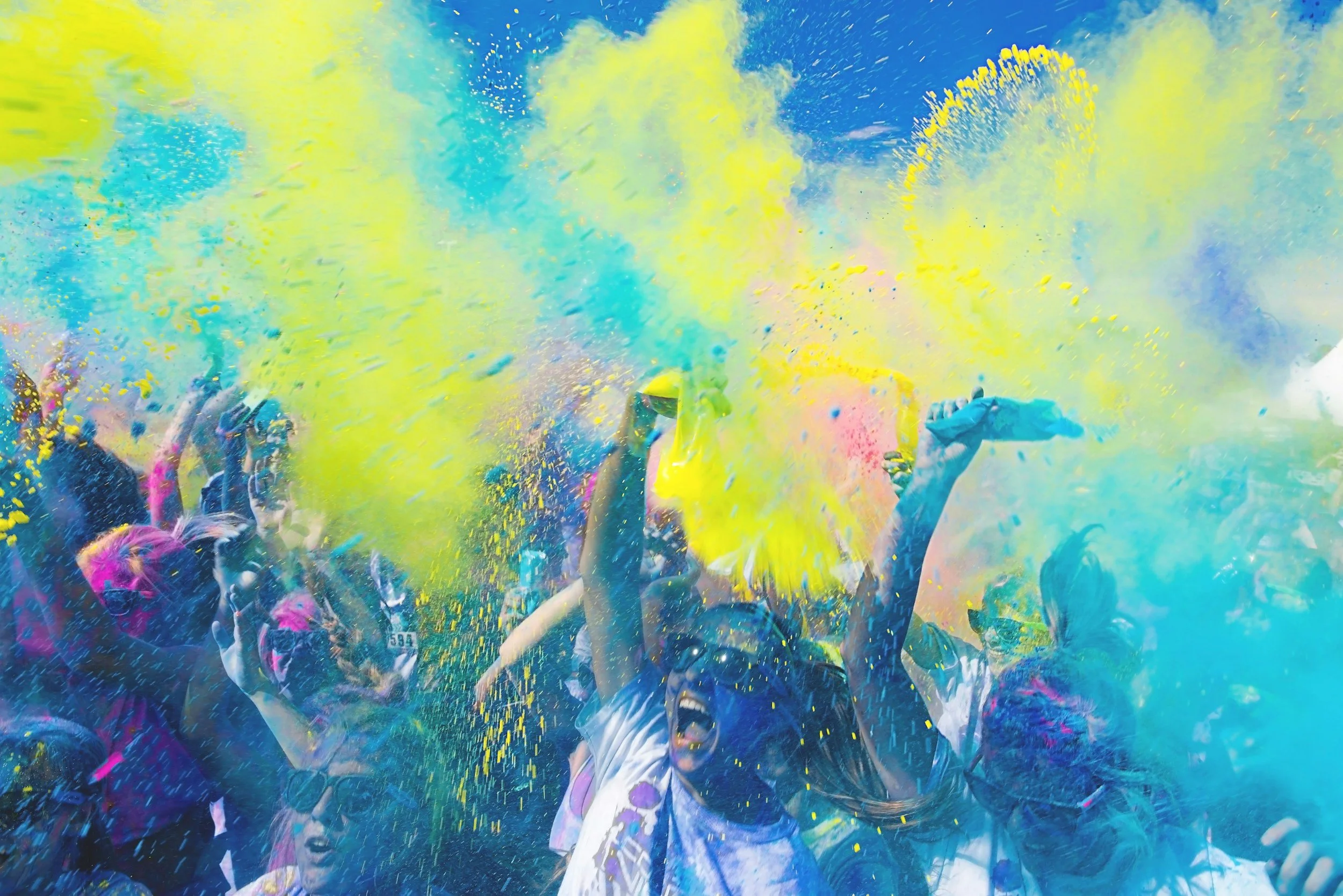 People celebrating with colorful powder during a festival or event.
