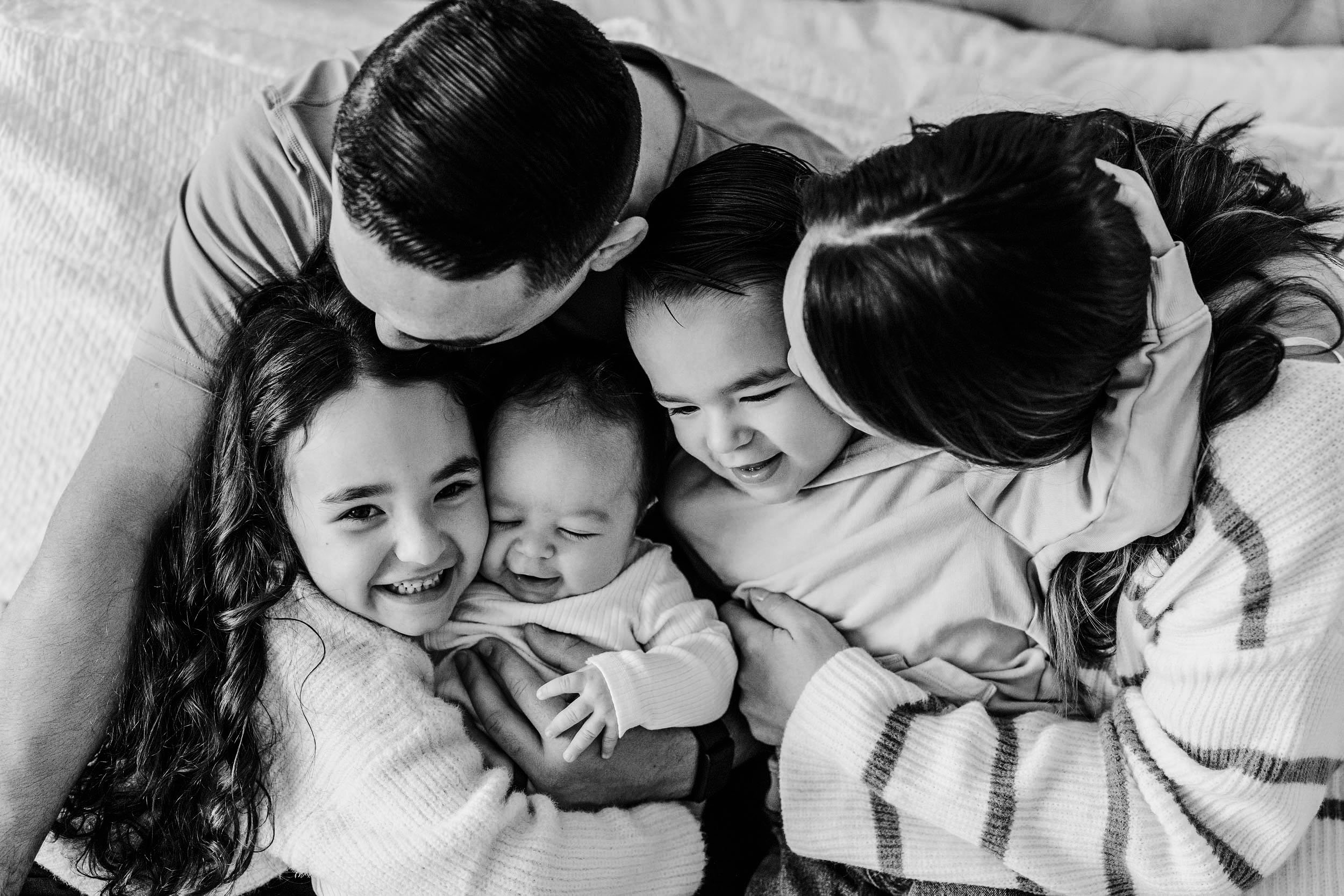 A young girl smiling and looking at a baby lying on a couch in a living room.