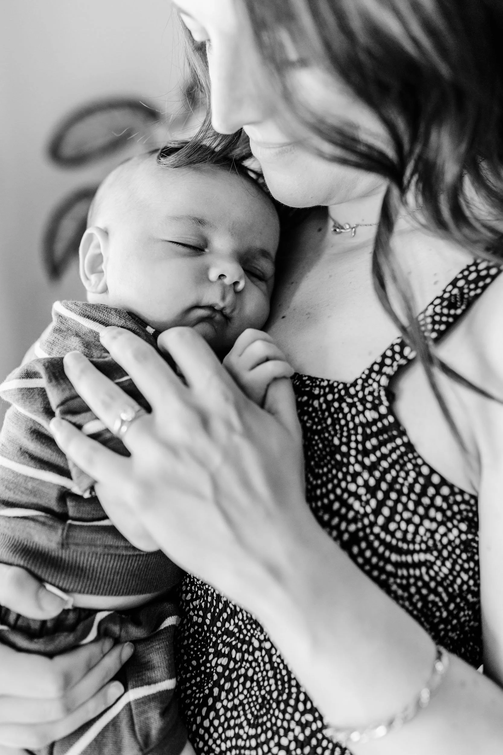 A woman holding a sleeping baby close to her chest, both with their eyes closed, in a tender moment.