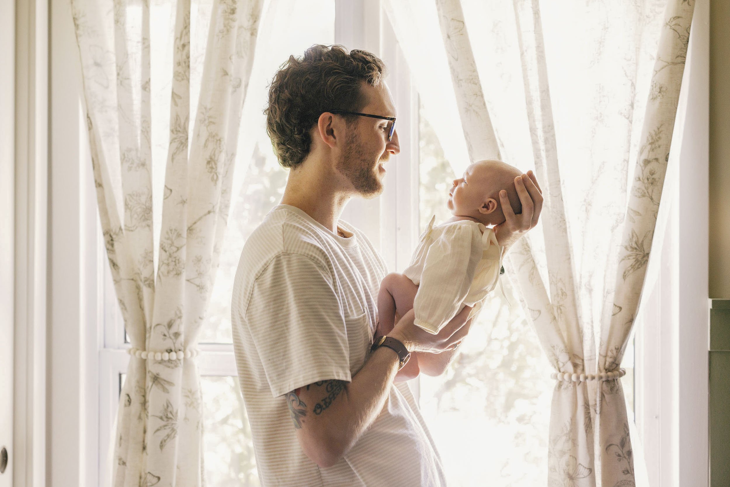 Family of four walking on a rocky trail during sunset in a natural landscape, with the sun low on the horizon and trees in the background.