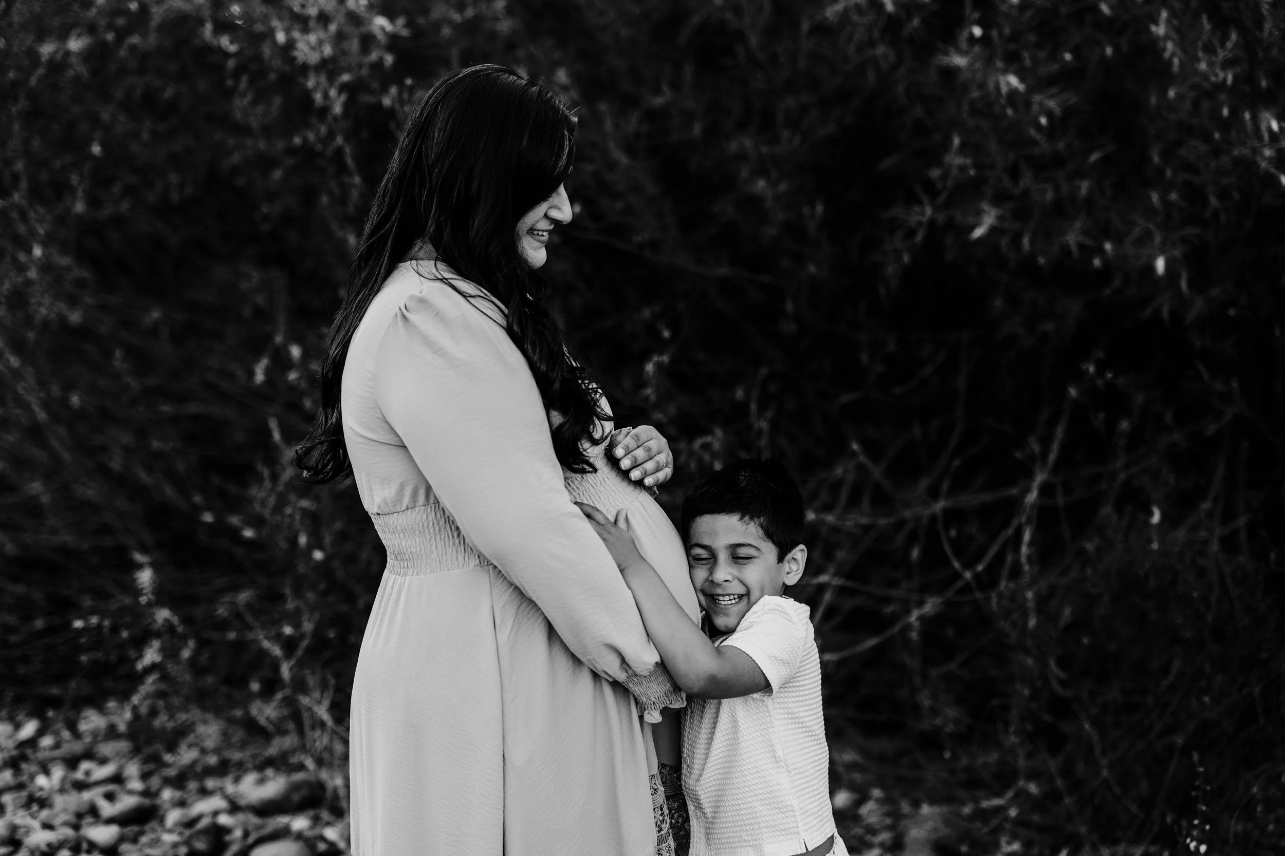 A boy hugs his mother's belly during maternity portraits with Roseville family photographer Amy Wright.