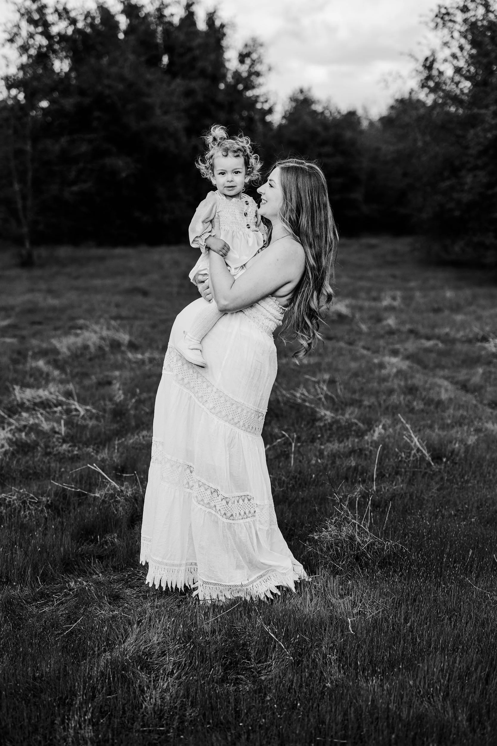 A pregnant mother holds her toddler on her belly during a maternity photo session with photographer Amy Wright in Roseville, California.