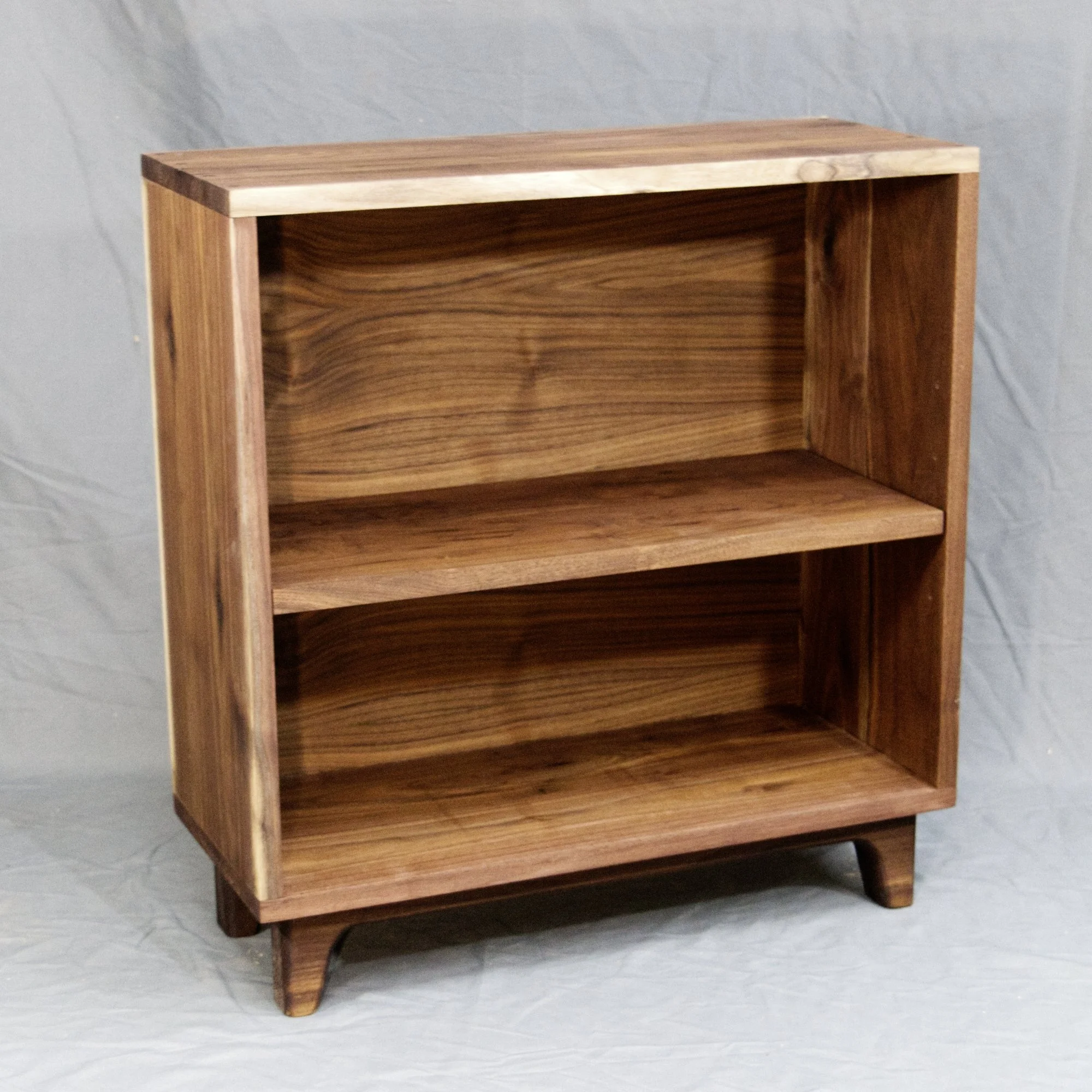This shaker style walnut bookcase features through-dowel joinery and has an adjustable shelf. This bookcase sits on a custom walnut leg base. 