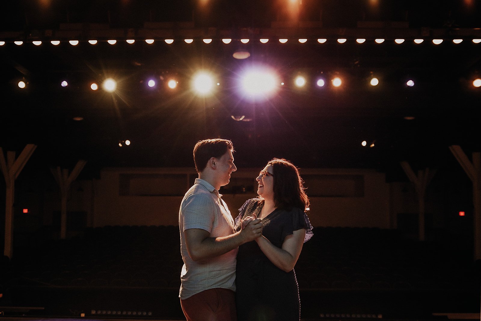 A couple dancing together on stage with bright lights overhead