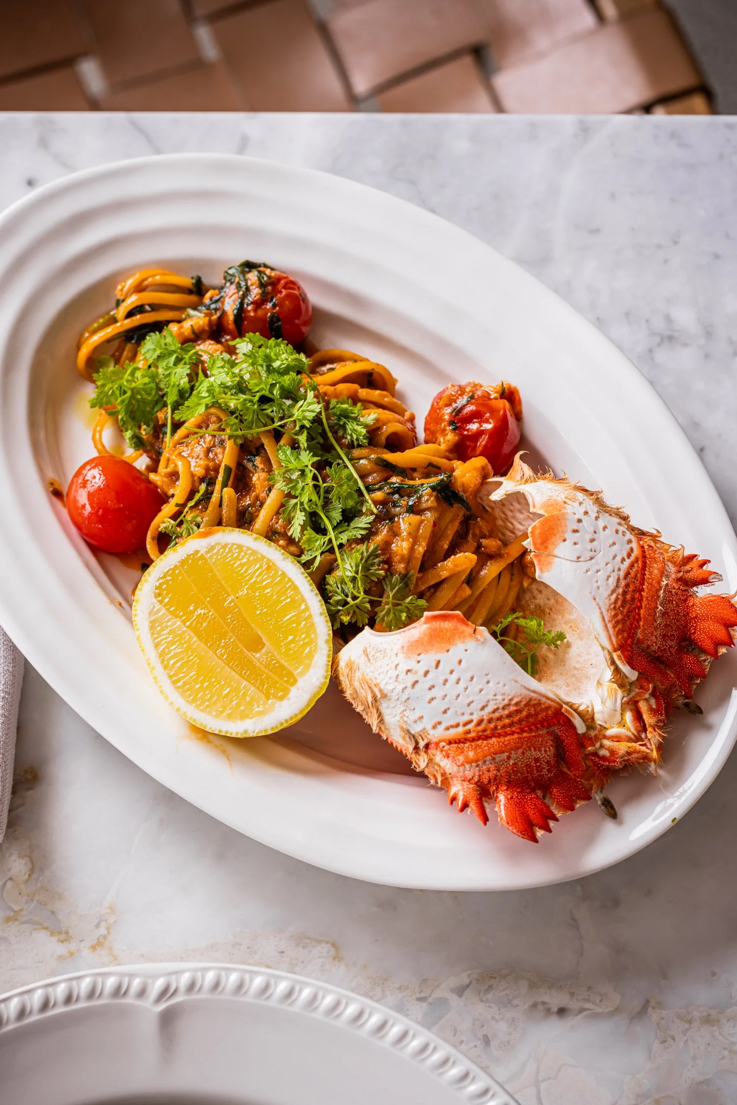 Restaurant meal of lobster, lemon and tomatoes on a share plate