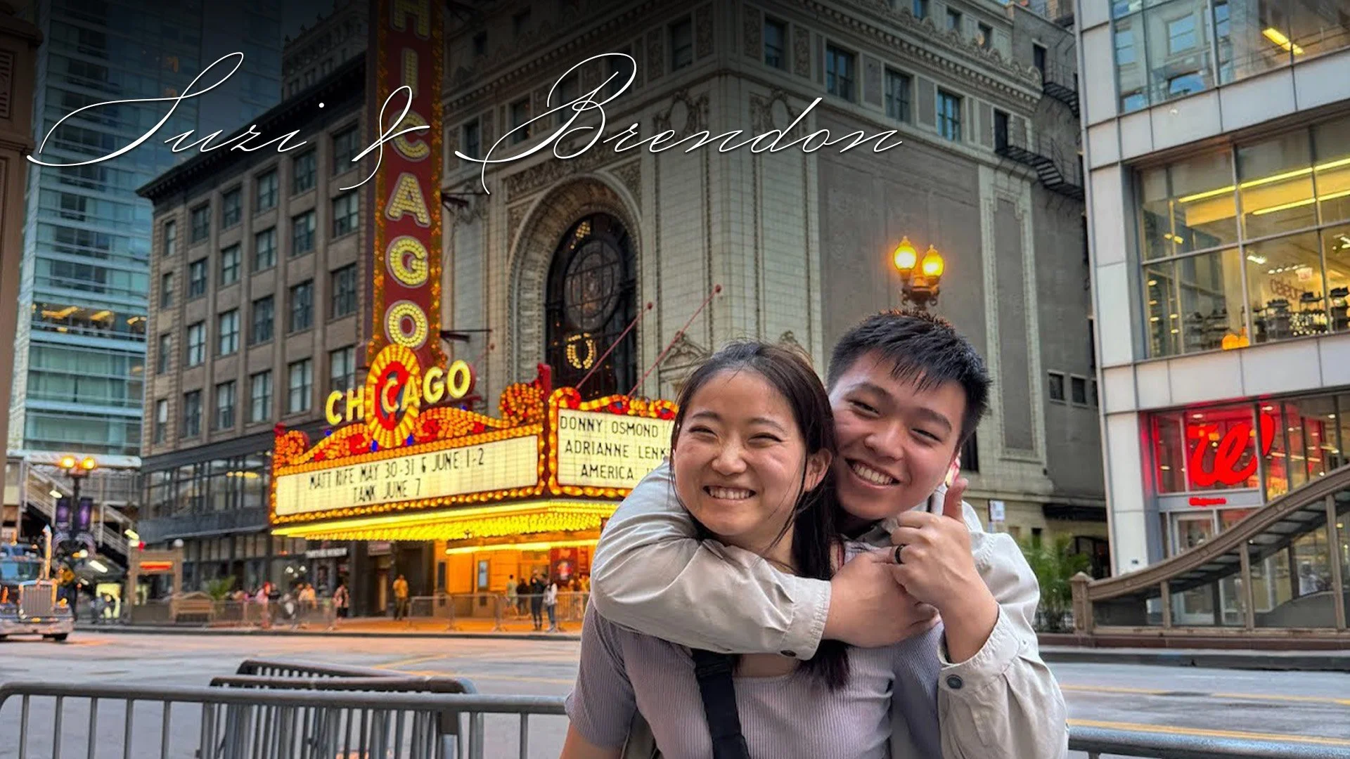 Two smiling people hugging in front of the Chicago theater marquee and historic building, in downtown Chicago