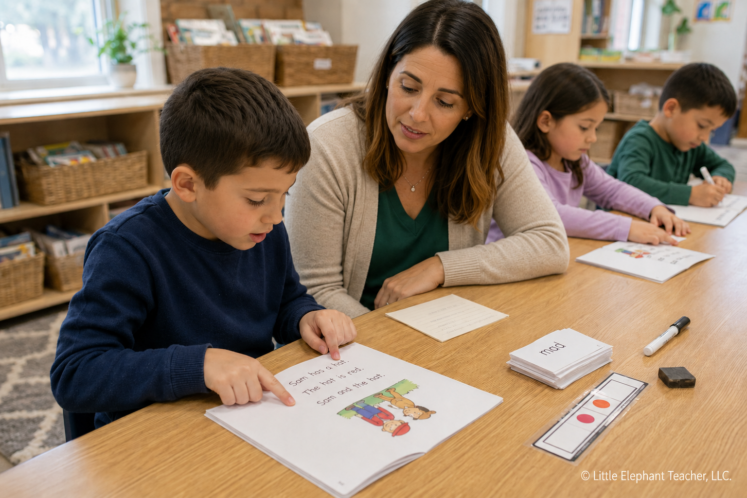 Elementary student reading a decodable text while a teacher listens during small-group phonics instruction.