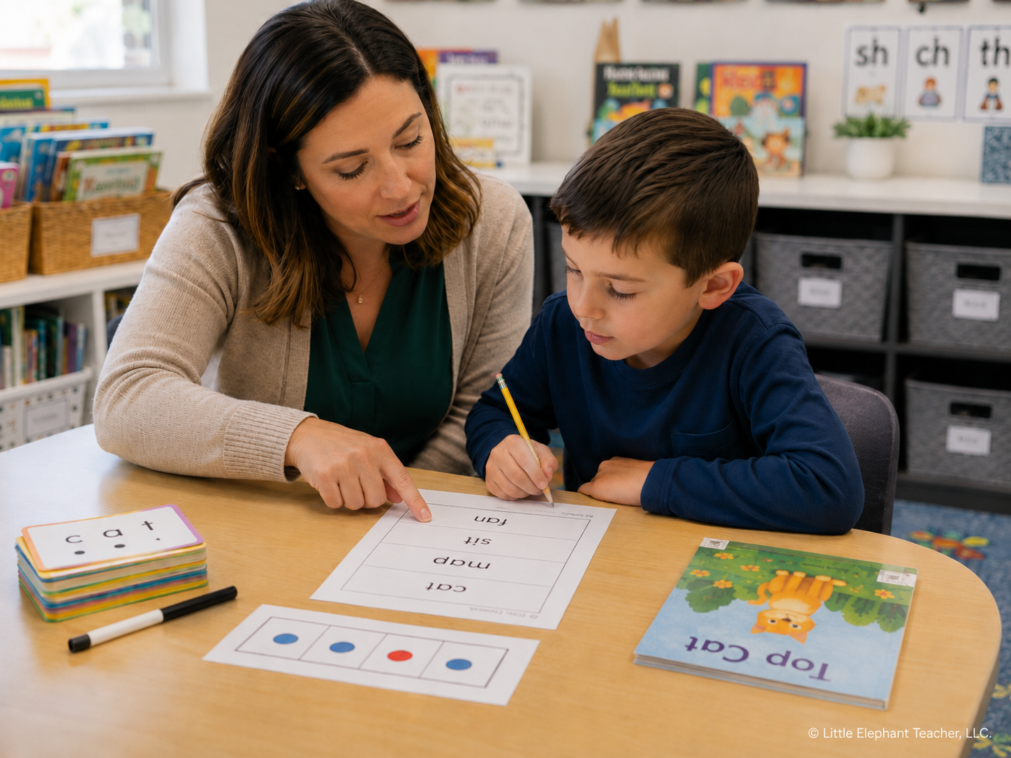 Teacher helping an elementary student blend and read CVC words during phonics instruction.