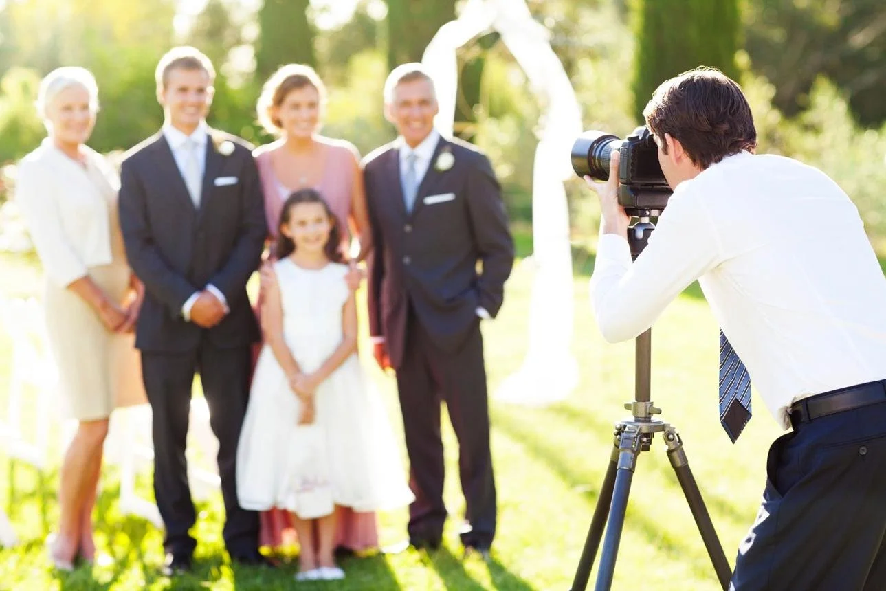 Photographer organising family members for wedding portraits after the ceremony