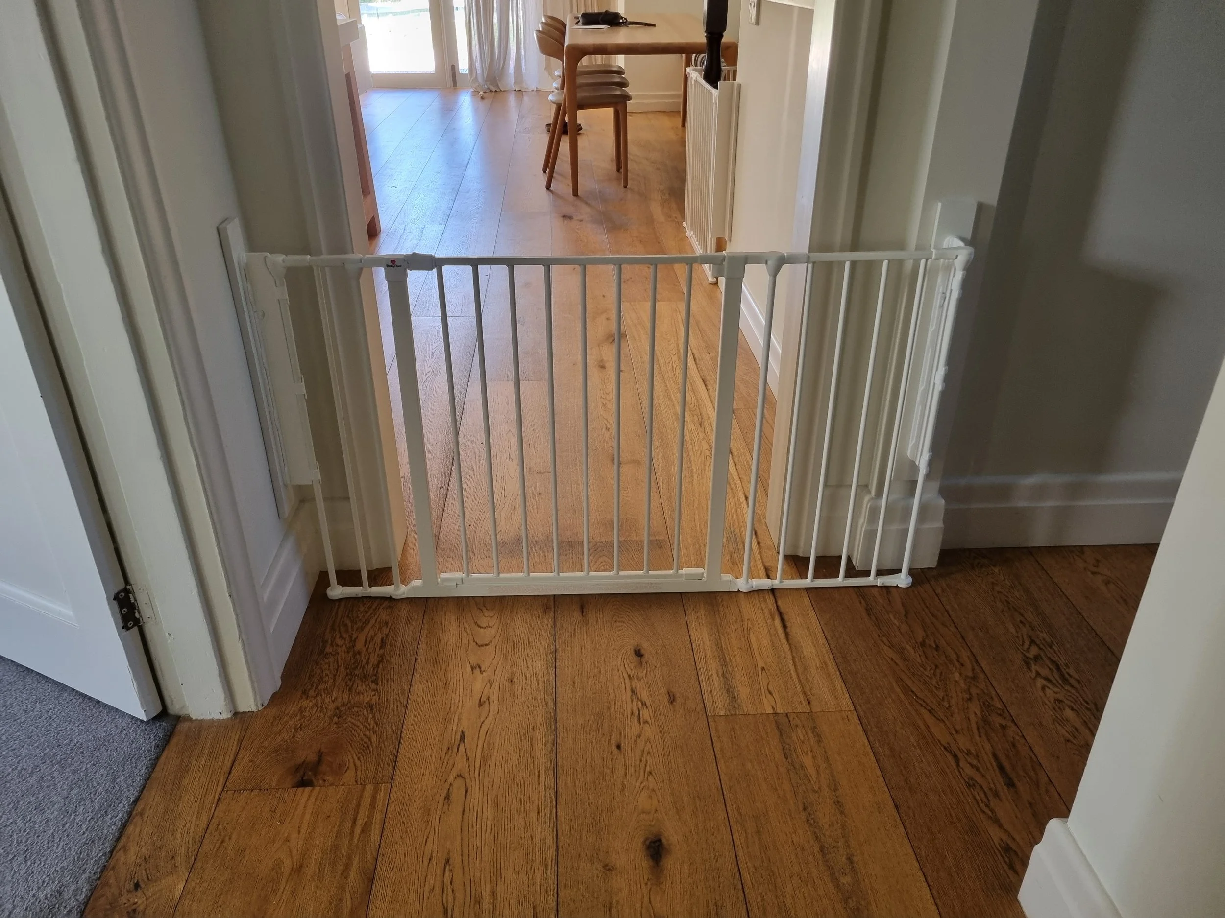White baby gate across a hallway on a timber floor