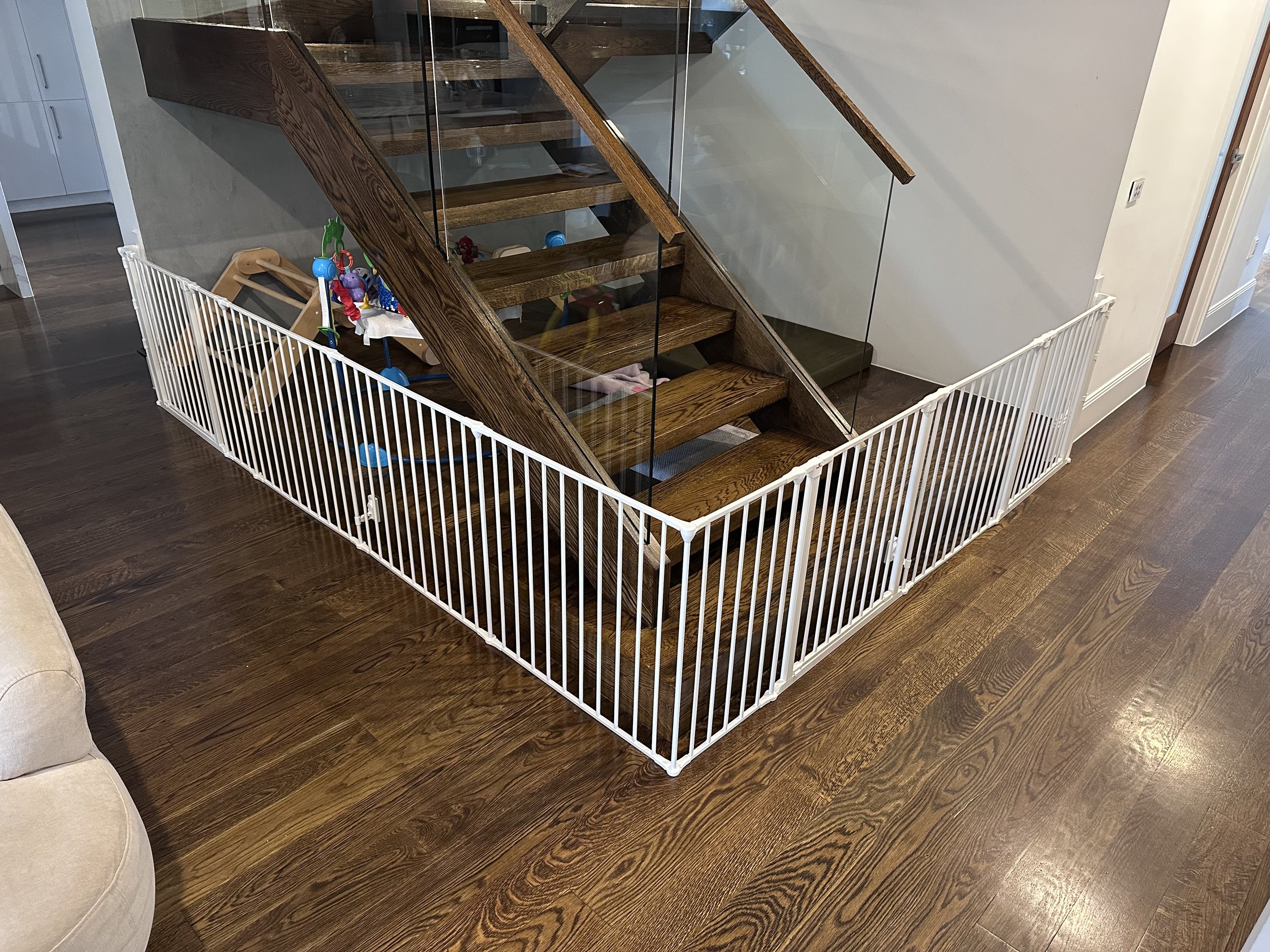 White gate closing off the space under open timber stairs