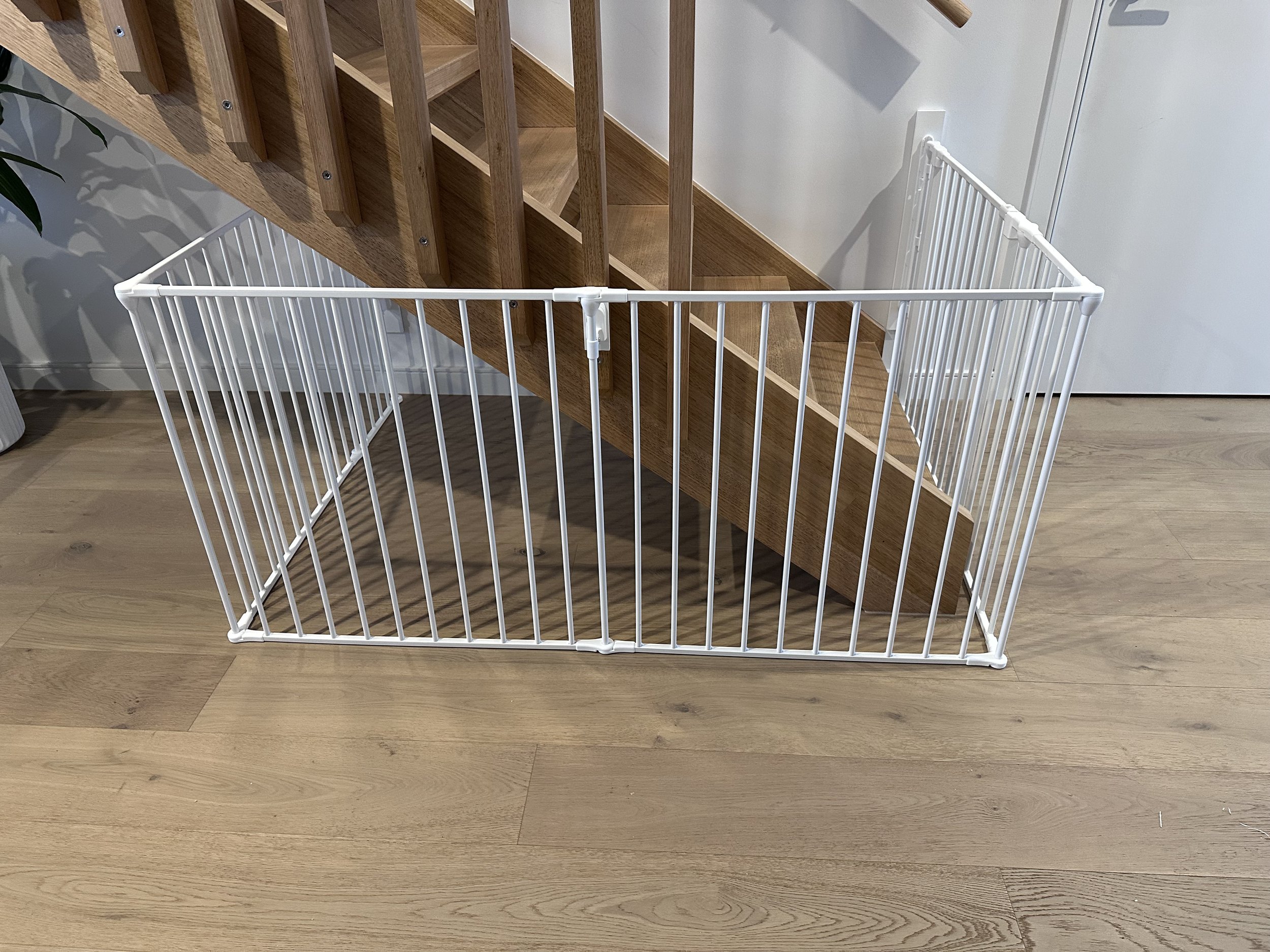 White gate enclosing the underside of timber stairs
