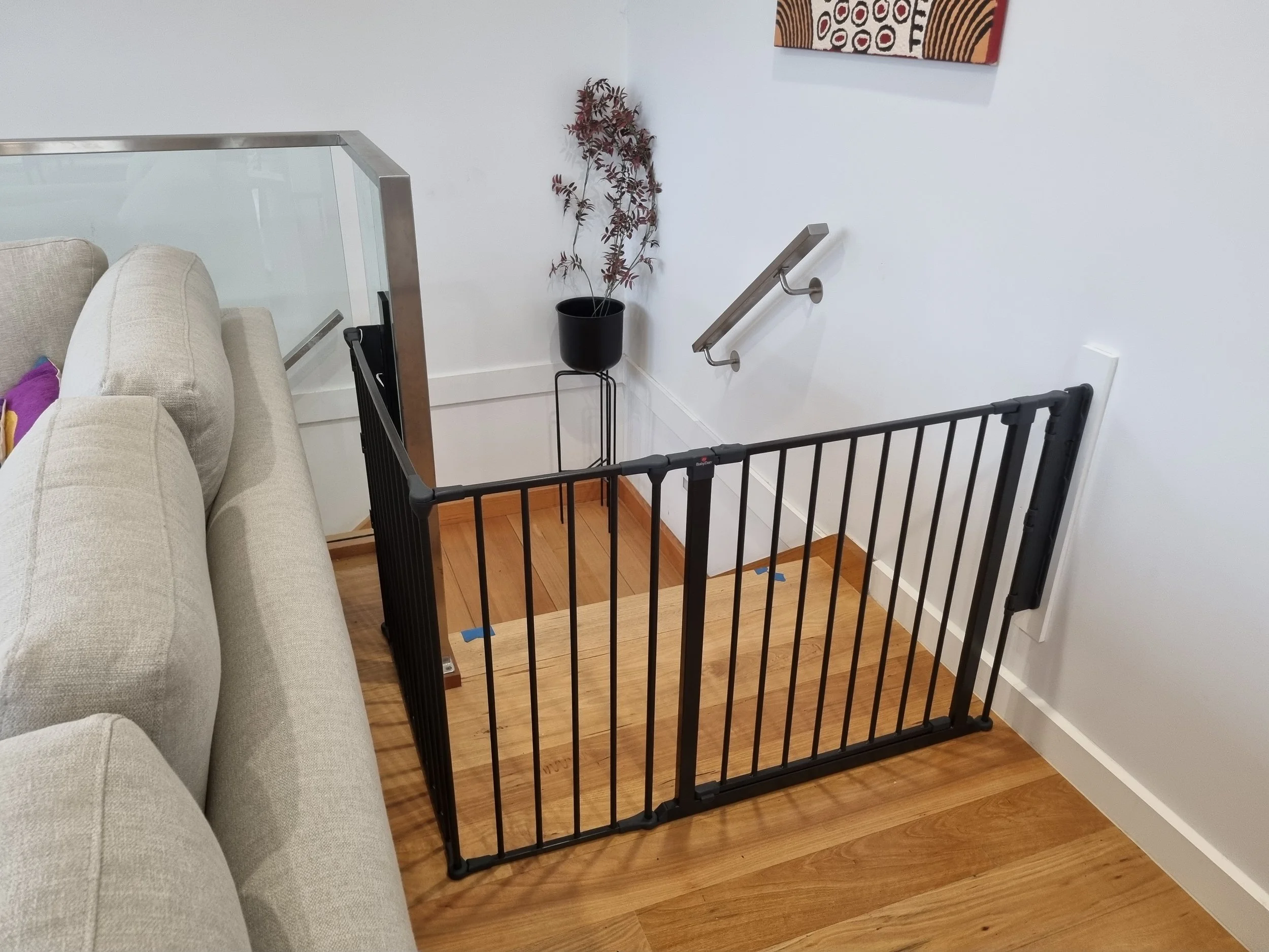 Black baby gate across an opening on a timber floor