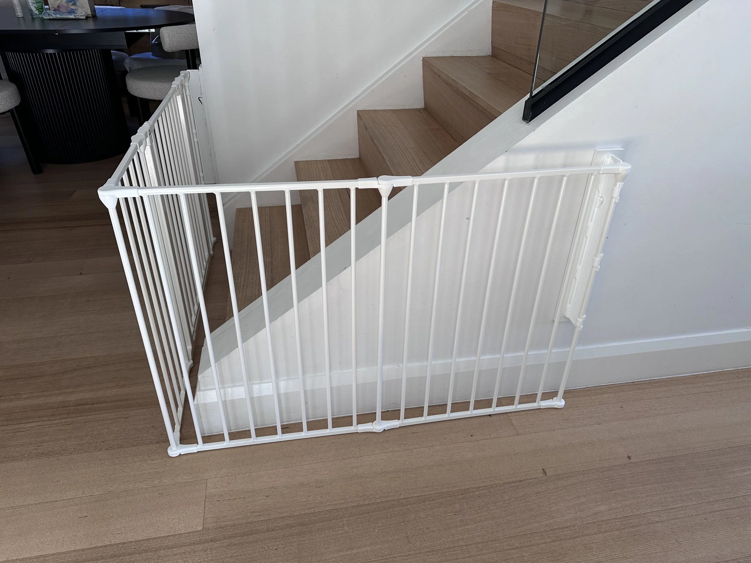 White gate enclosing the bottom of stairs beside a white wall
