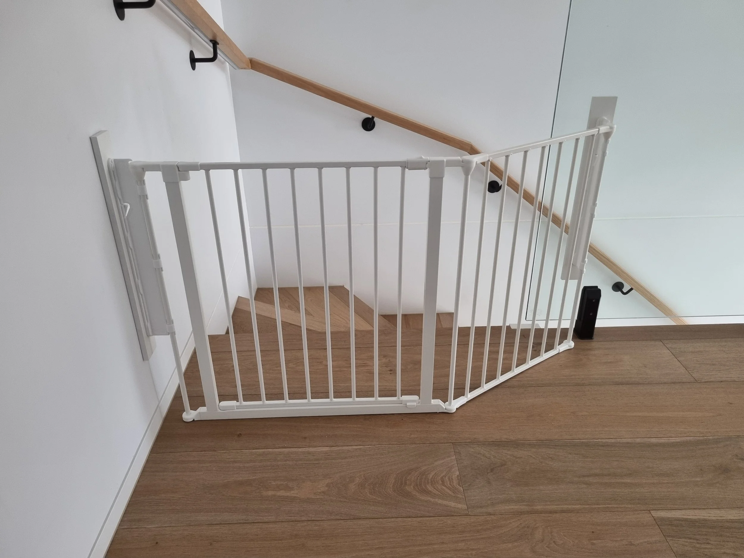 White corner baby gate around the top of timber stairs